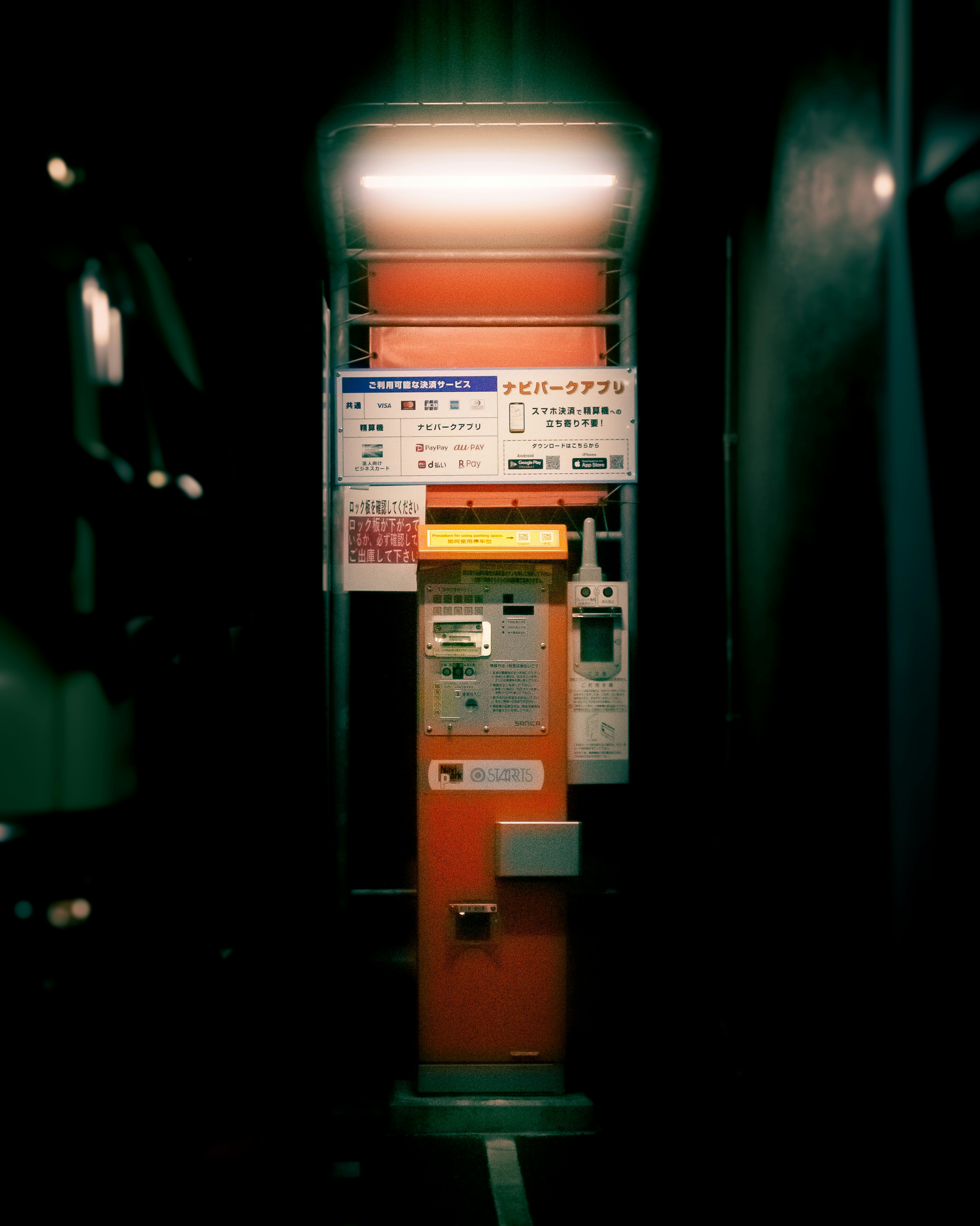 An orange public telephone booth standing in a dimly lit corridor