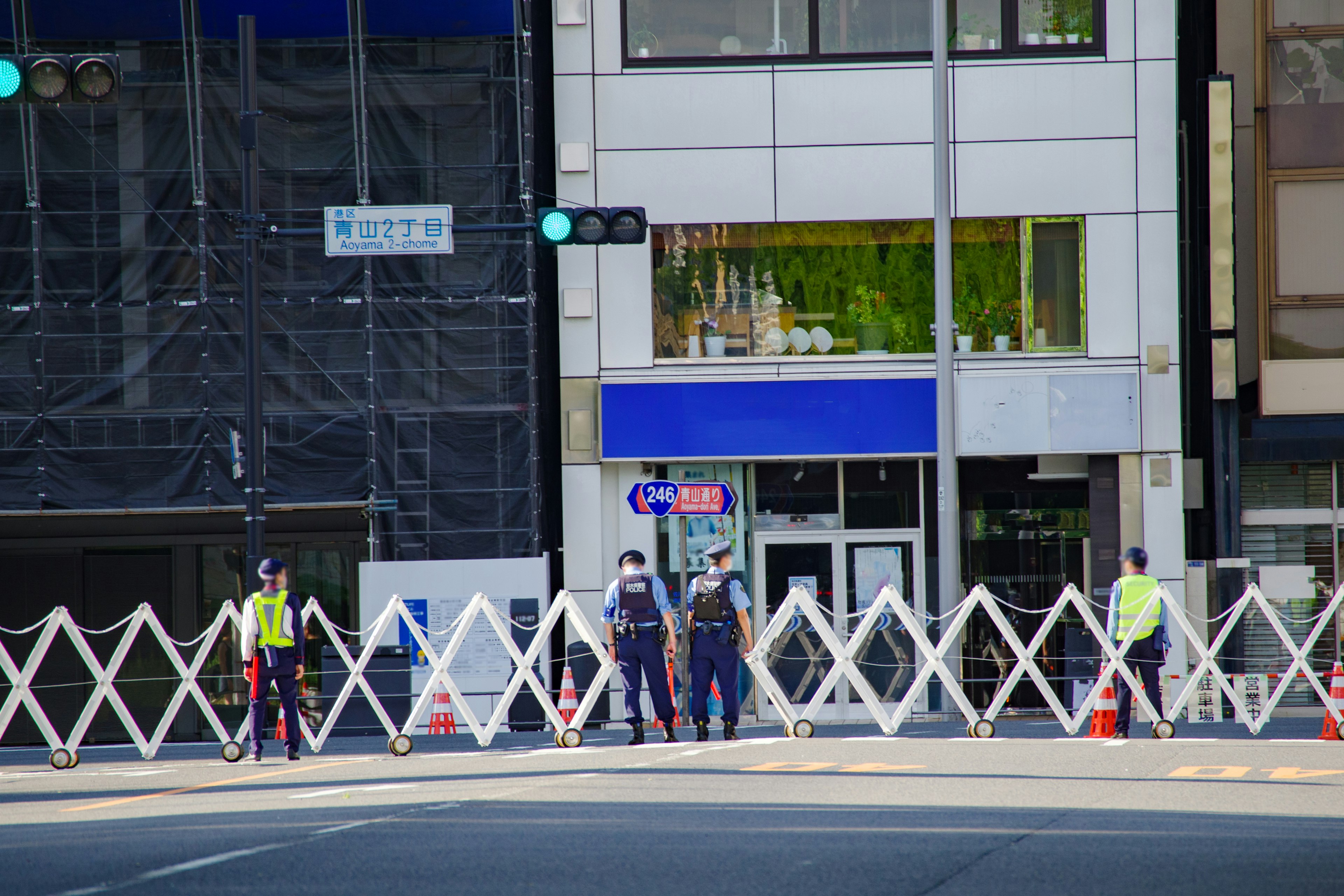 Security personnel by a road barrier with a blue sign building