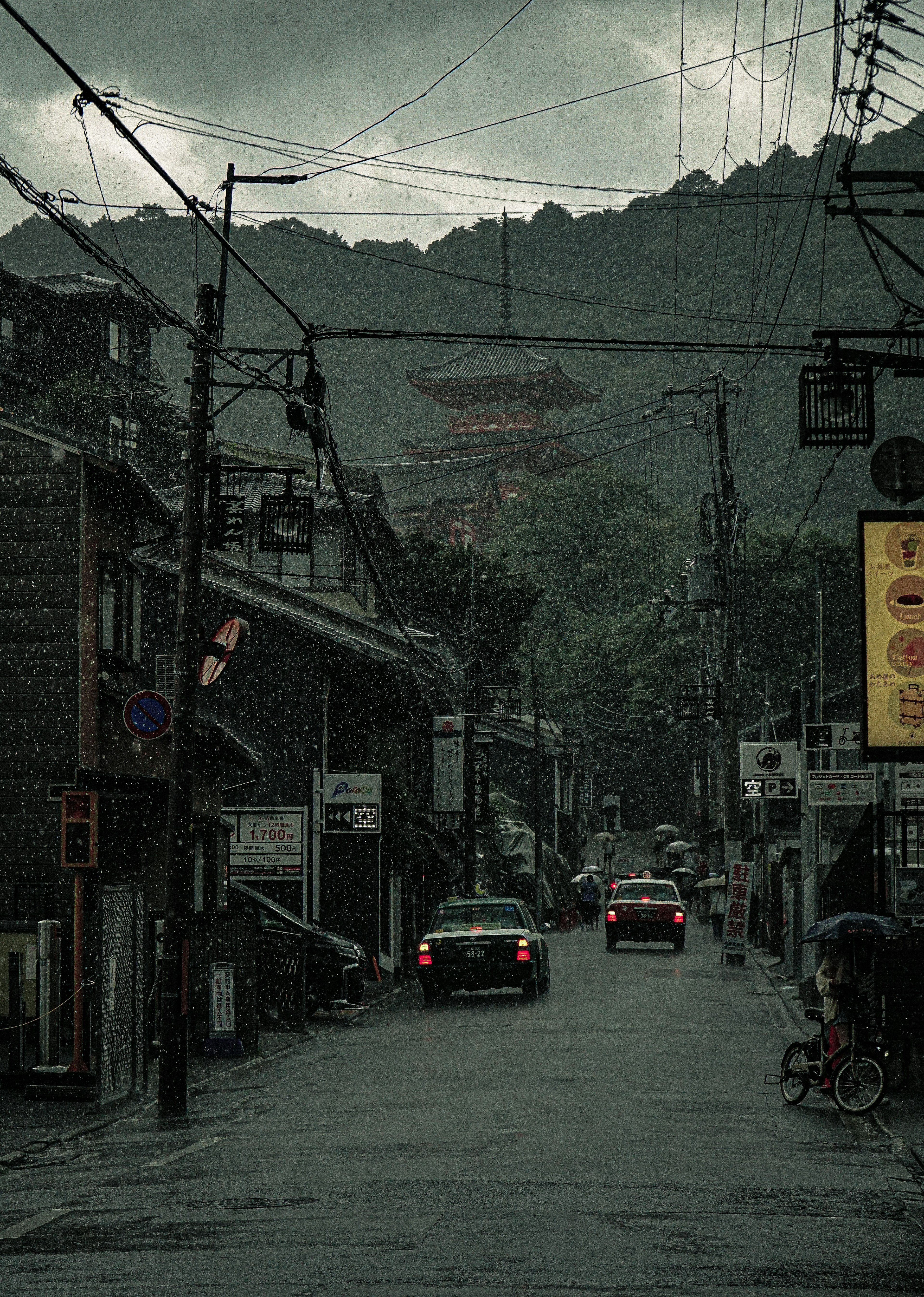 Quiet street scene with buildings and mountains in the background under rain