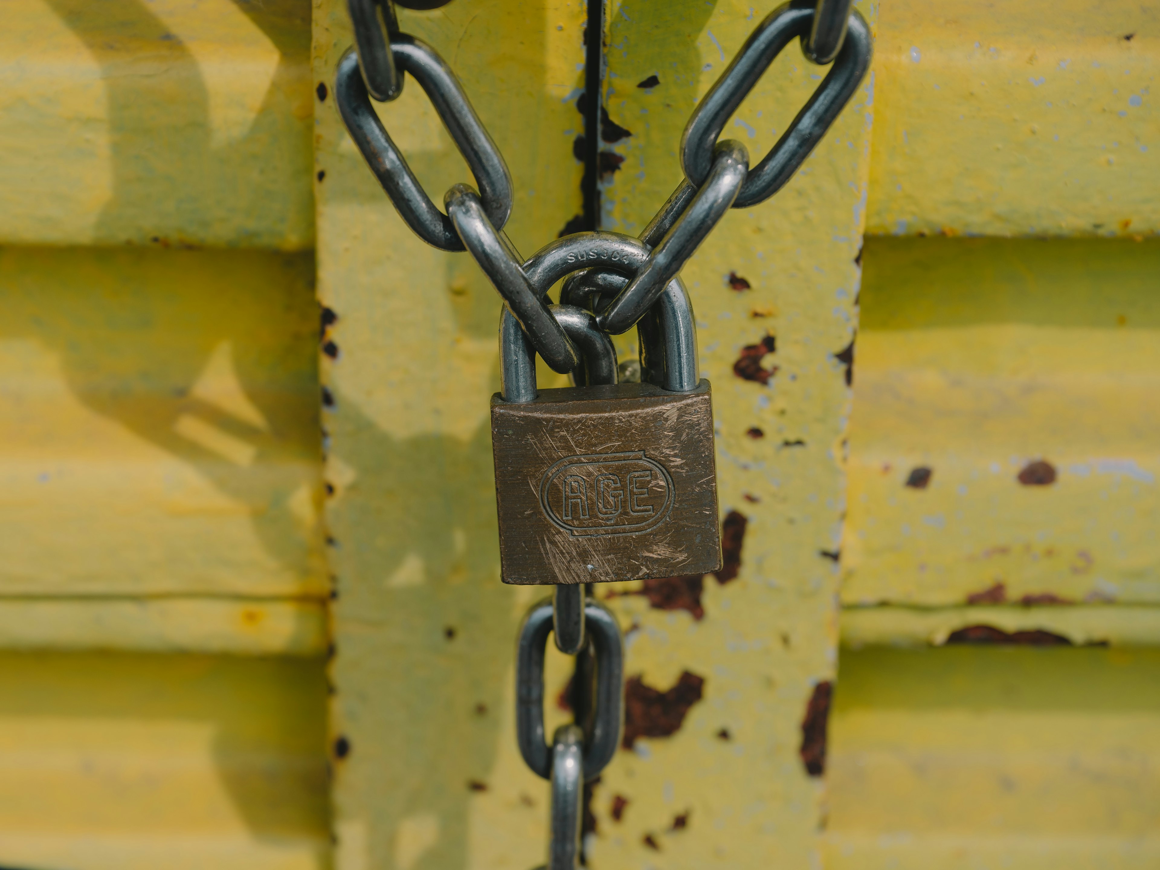 Old padlock and metal chain on a yellow door