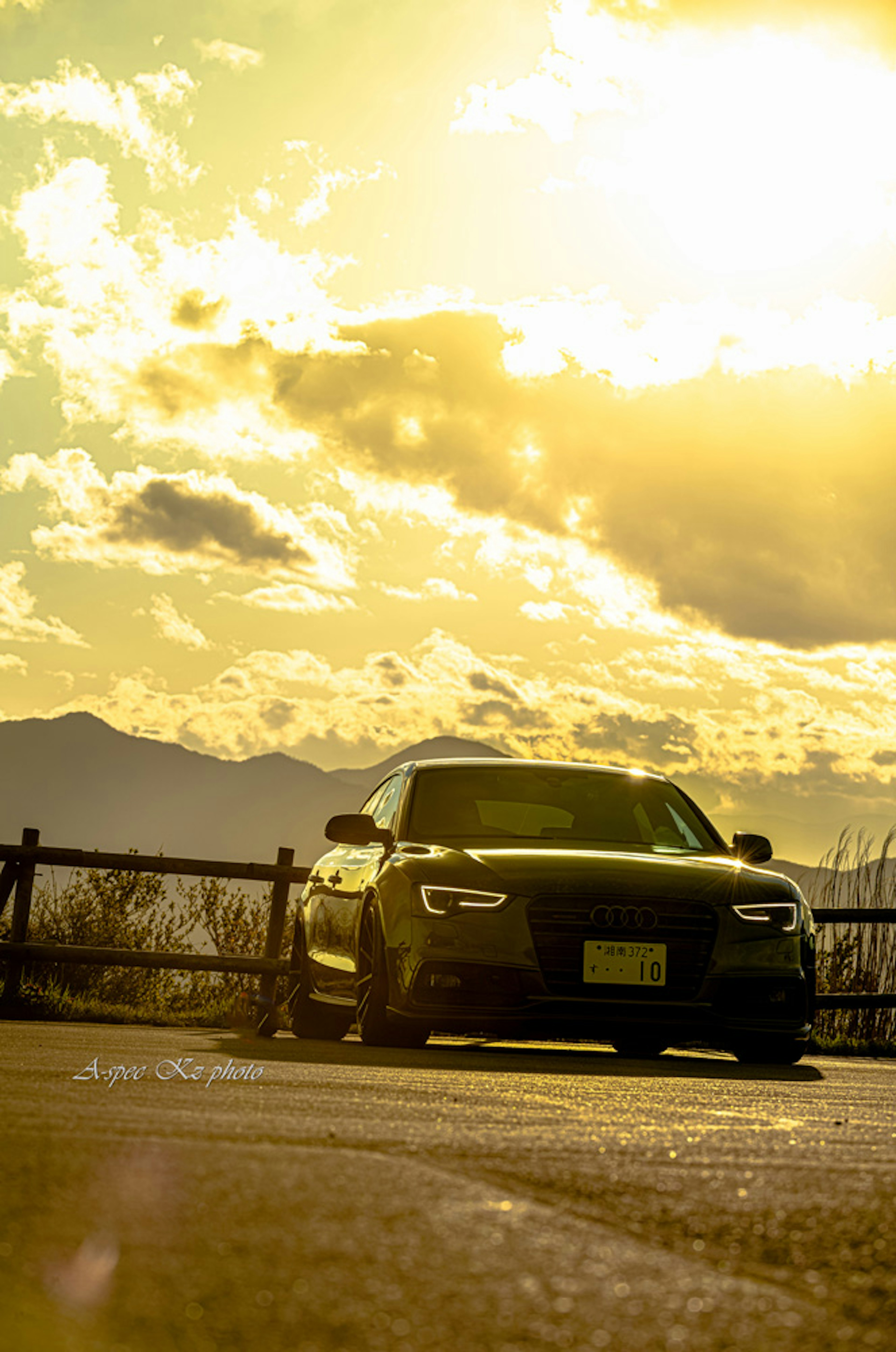 Un coche negro con un fondo de atardecer y silueta de montaña