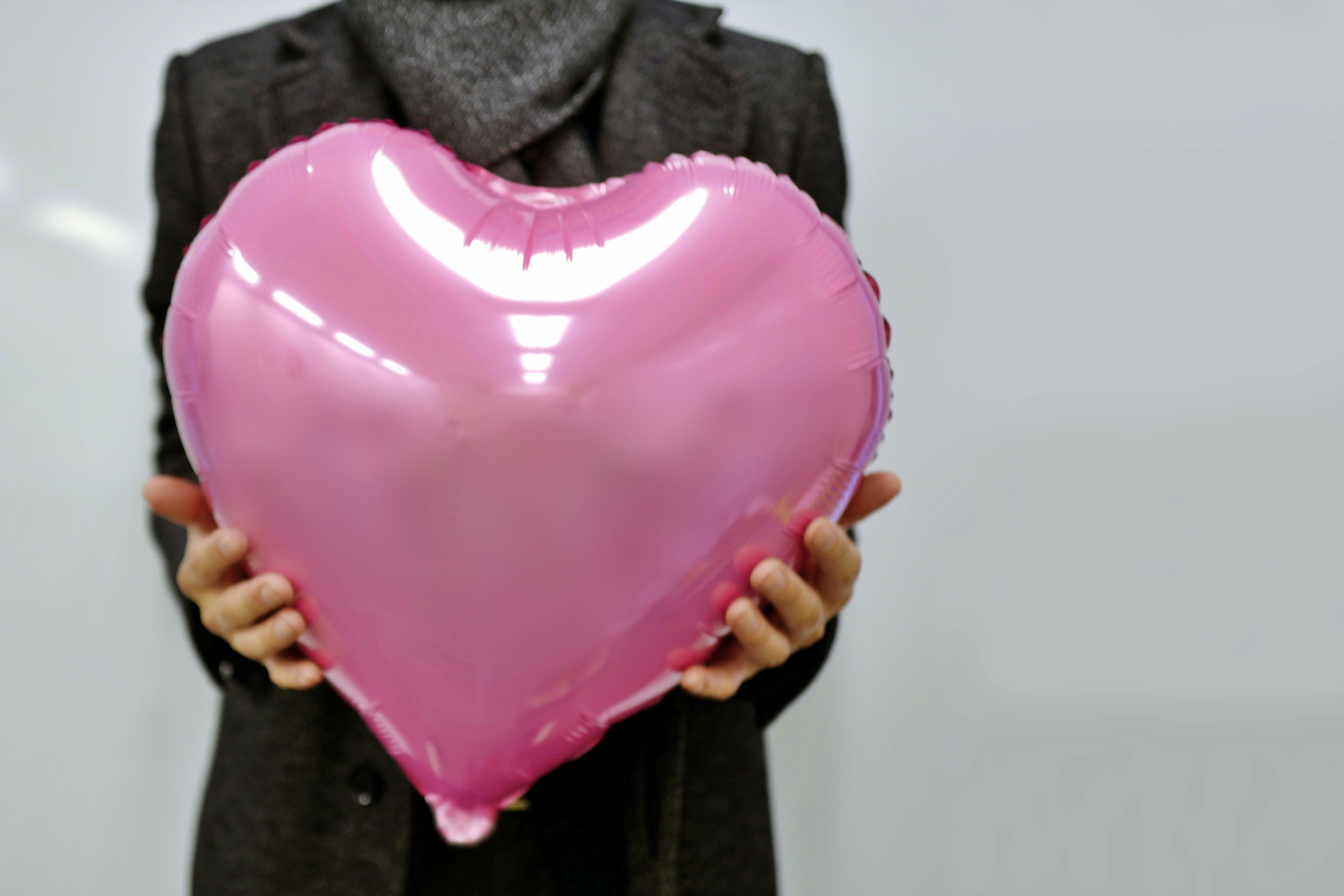 Person holding a large pink heart-shaped balloon