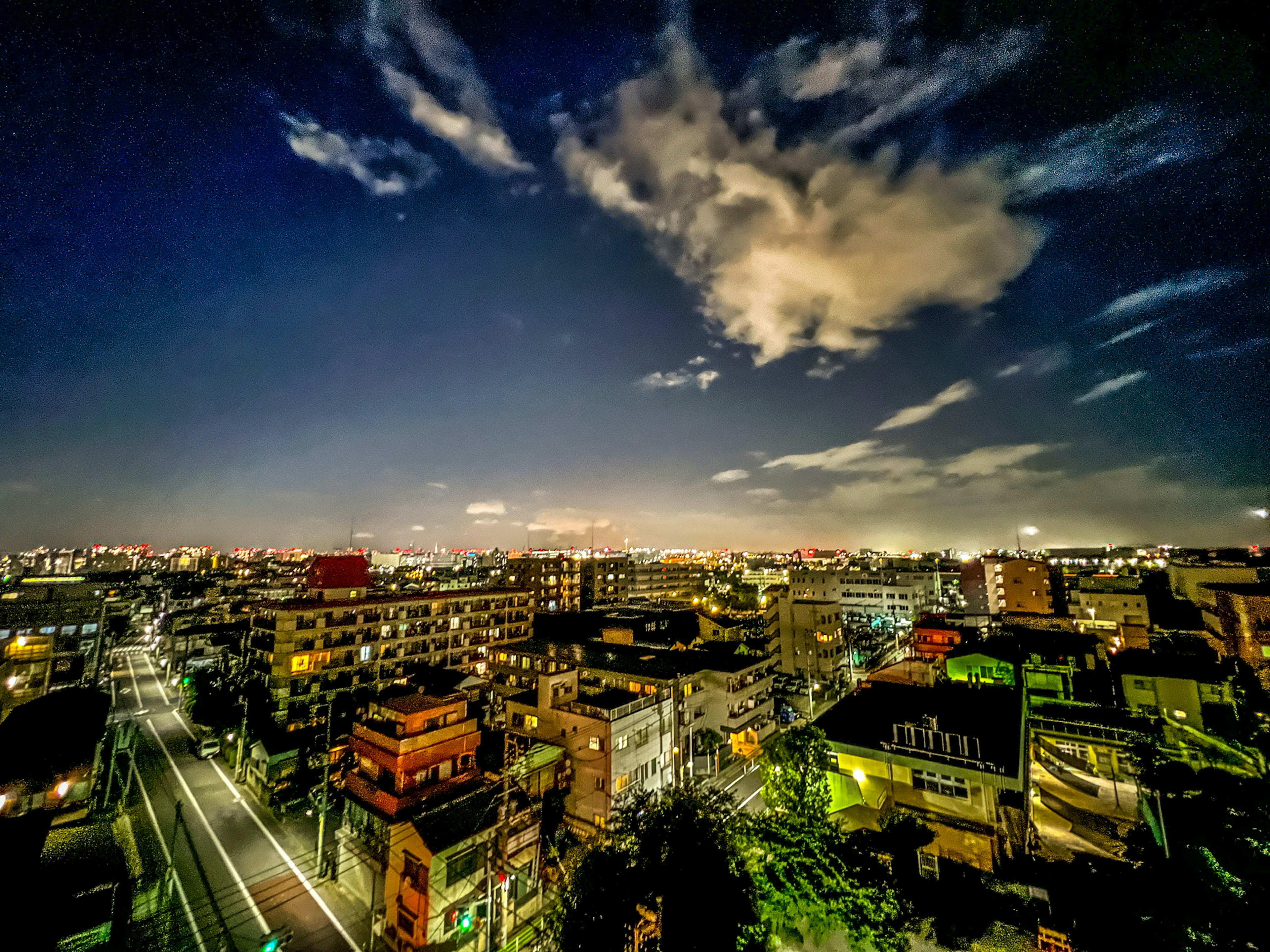 都市の夜景を捉えた広角写真　雲が浮かぶ空と明るい街灯が印象的