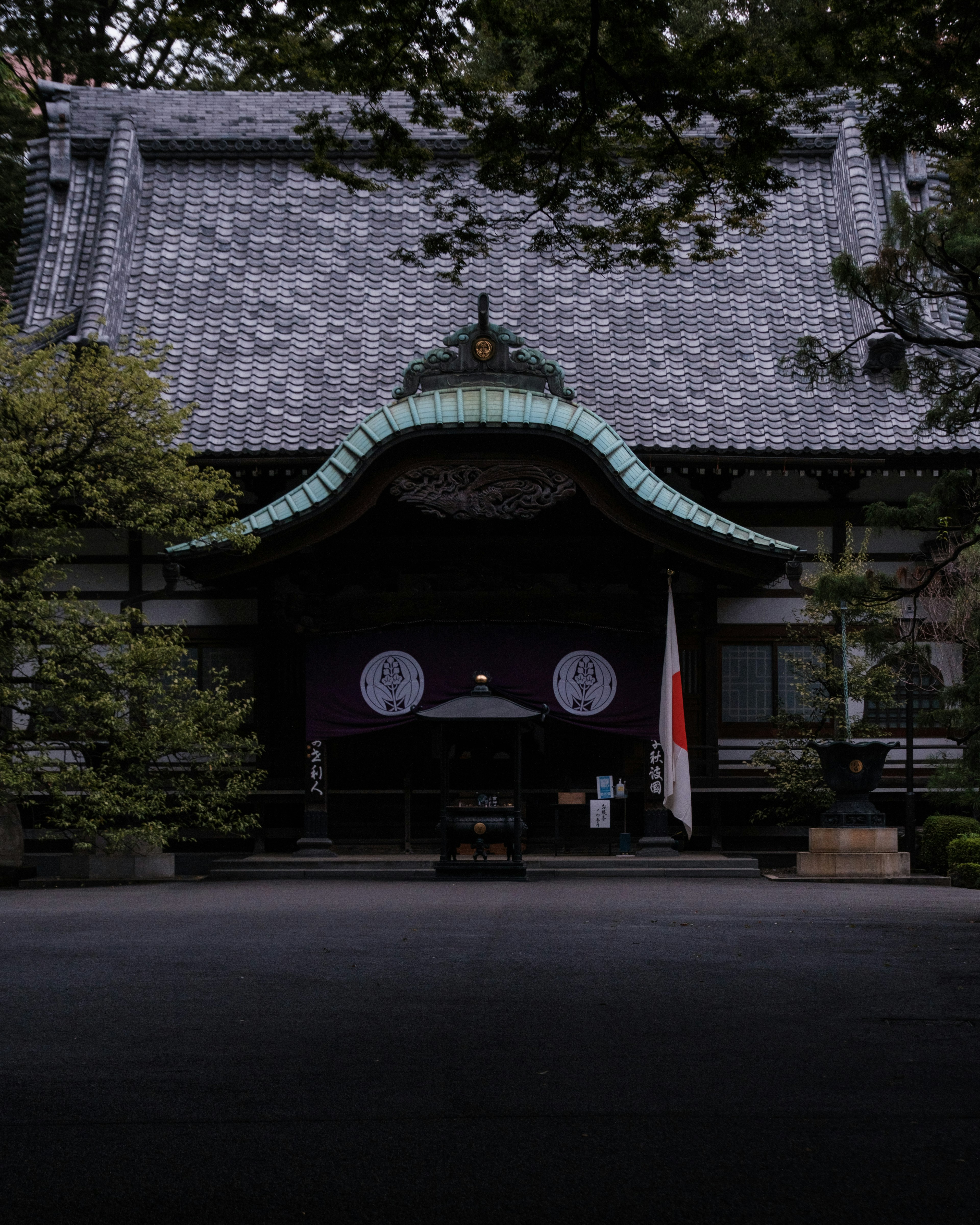 Traditional Japanese building exterior with a green roof and national flag in front