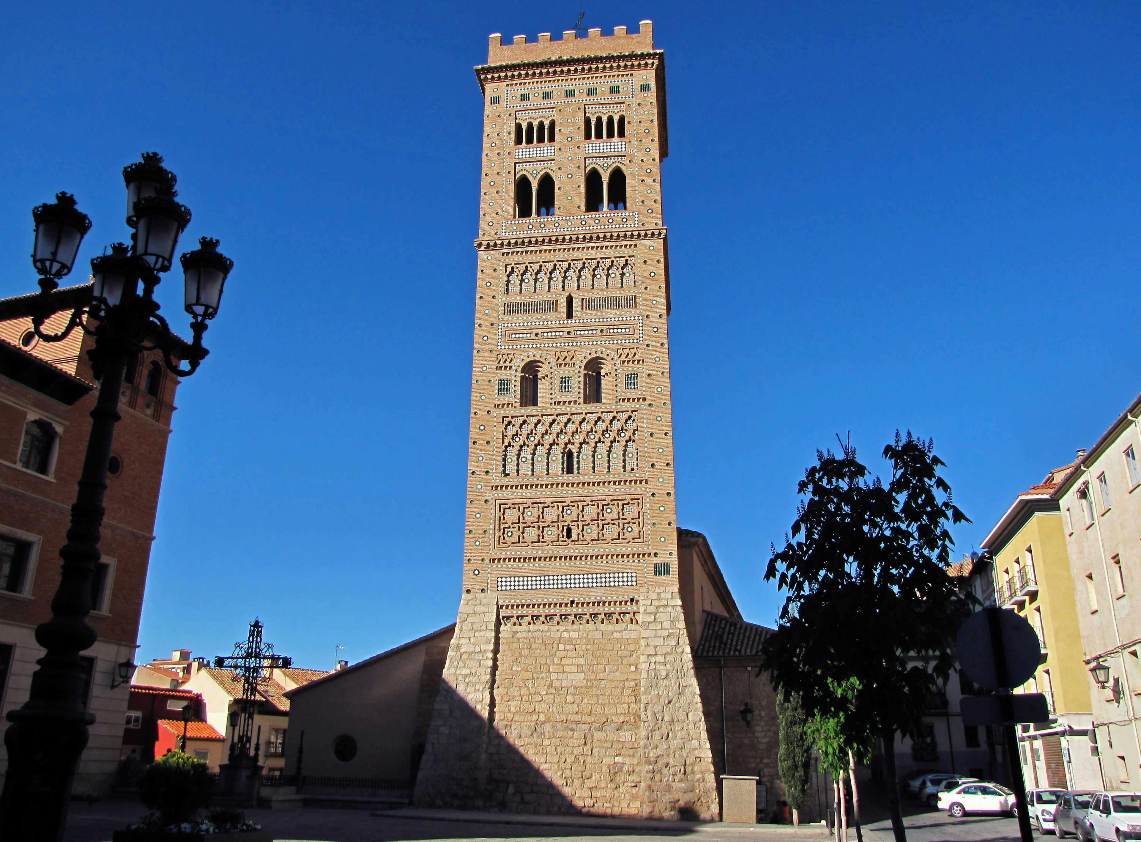 Alto campanile di pietra sotto un cielo blu con edifici circostanti