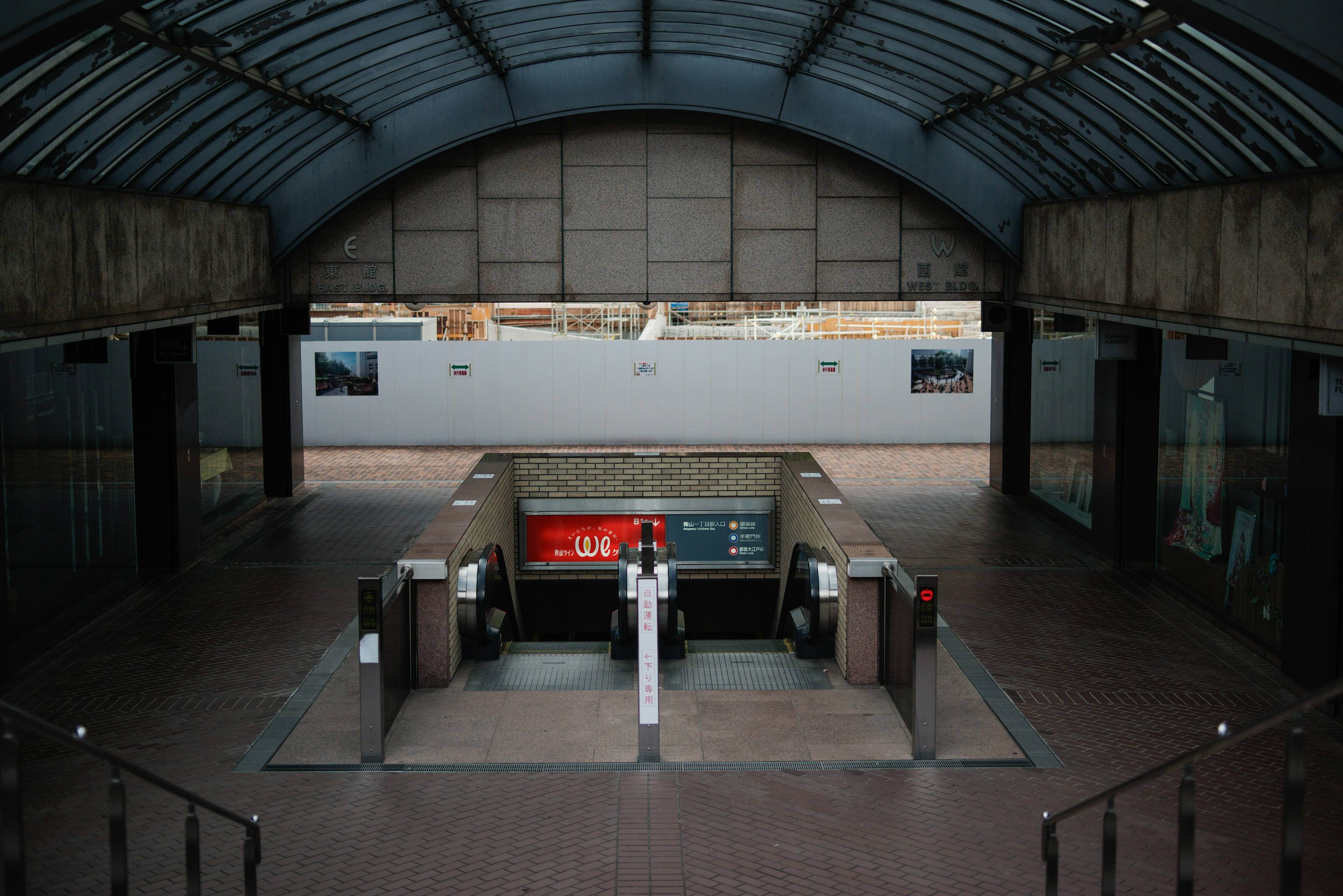 มุมมองกว้างขวางของทางเข้าของสถานีรถไฟใต้ดินที่มีเครื่องกั้นตั๋วและเพดานโลหะรูปโค้ง