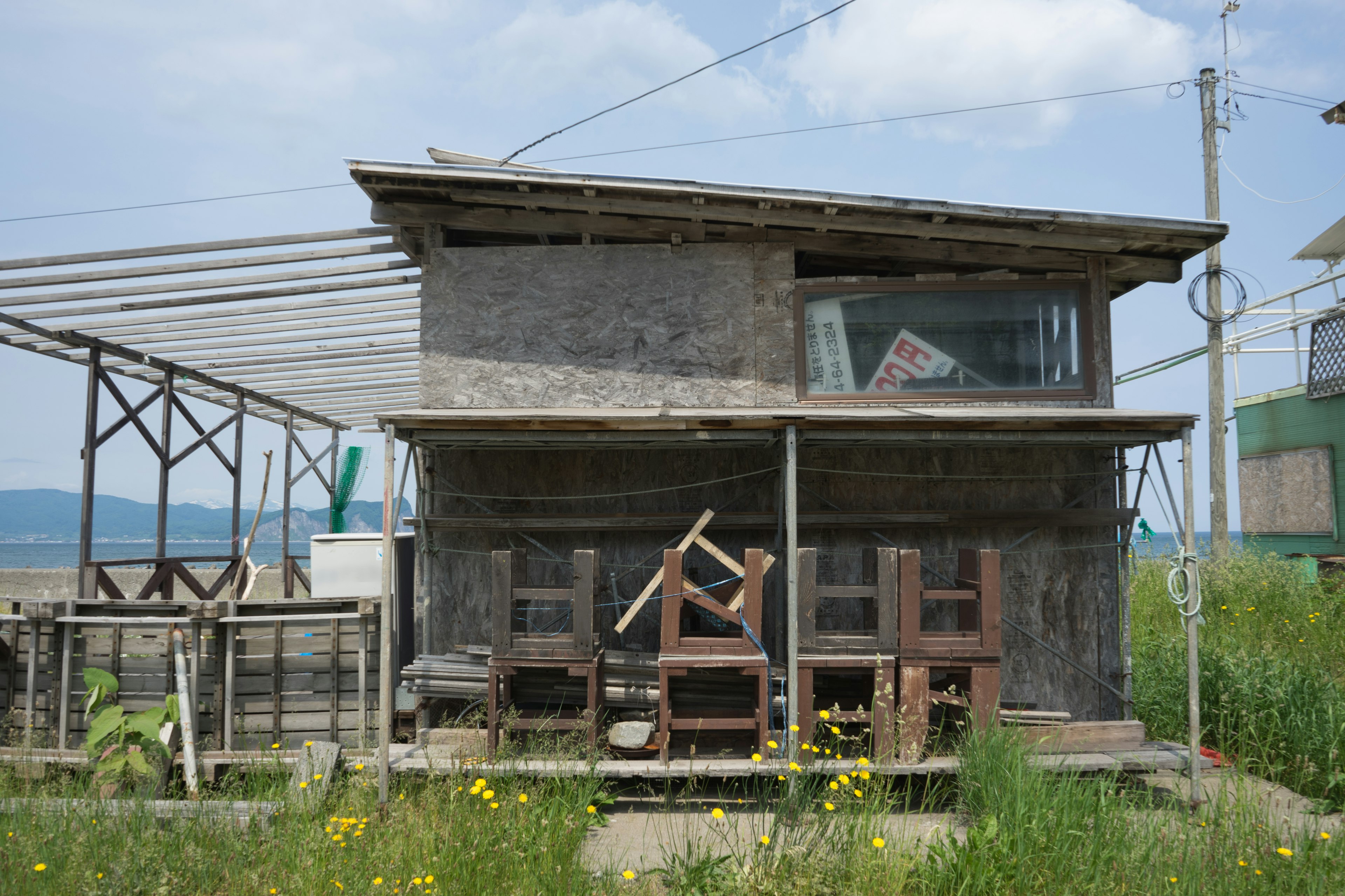 草に囲まれた木造の家屋と周囲の構造物の風景