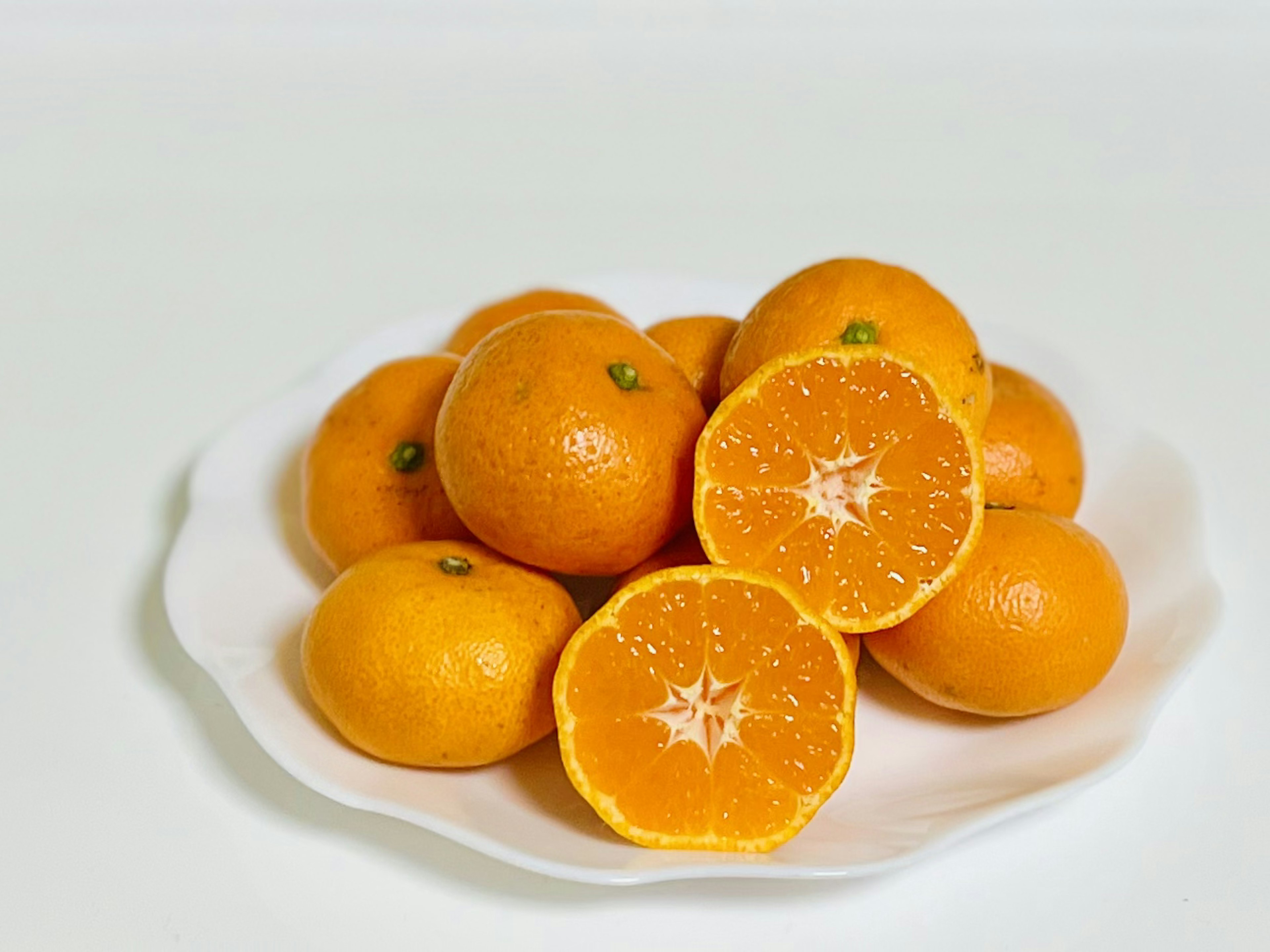 Un tas d'oranges sur une assiette blanche avec une orange coupée