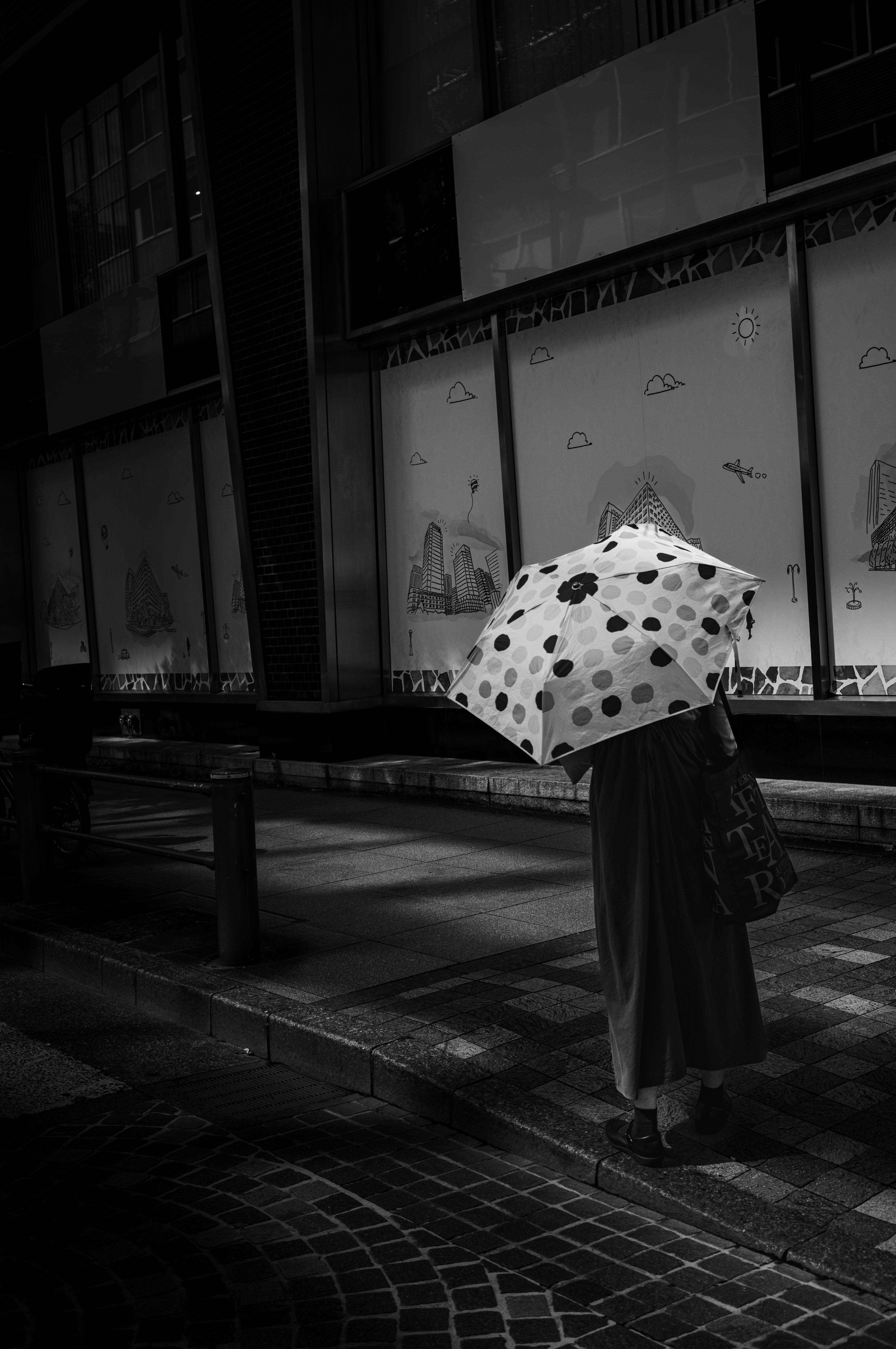 Persona che cammina in una città con un ombrello a pois