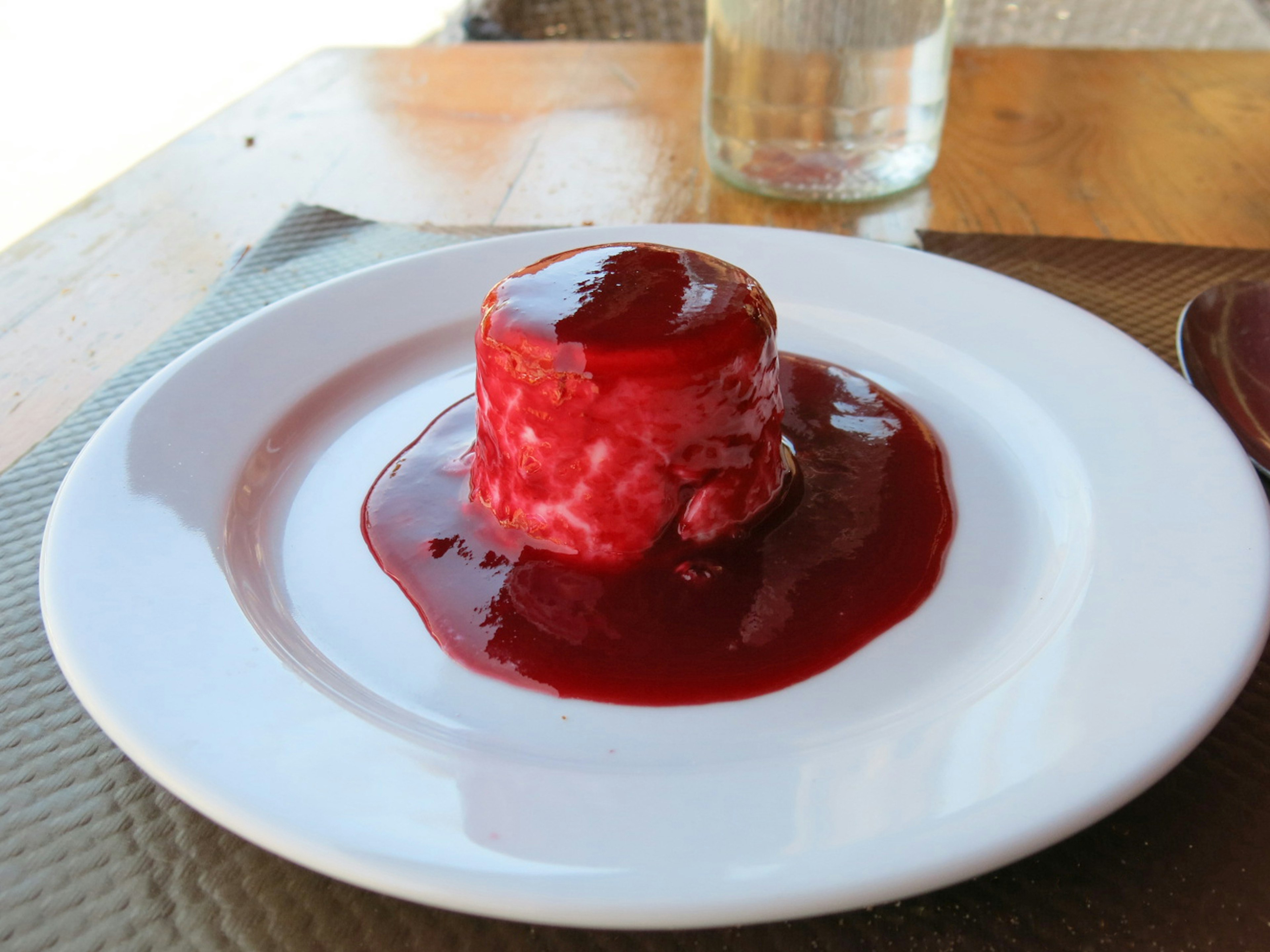 Ein kleiner Dessertkuchen mit roter Sauce auf einem weißen Teller