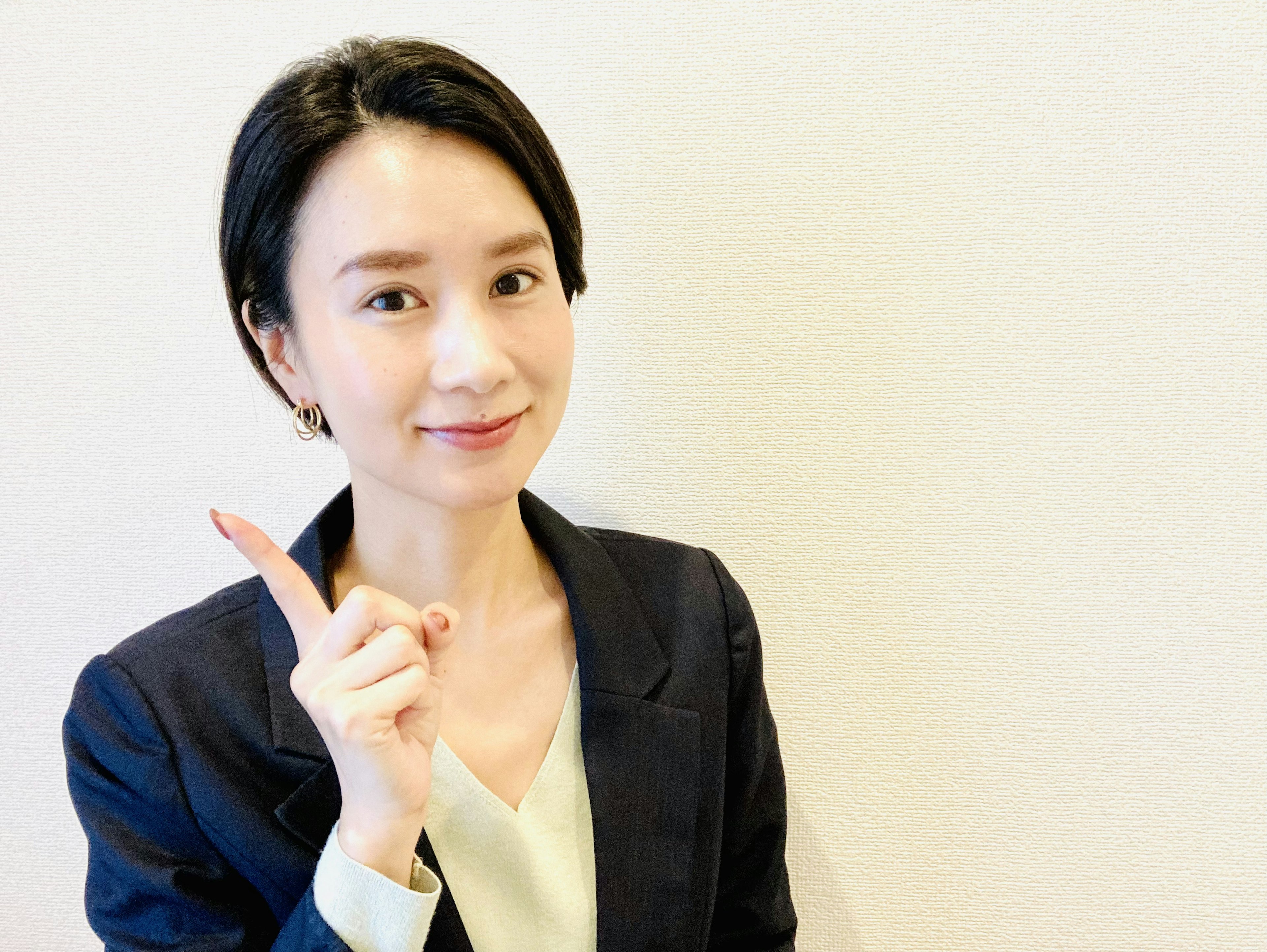 A woman in a business suit smiling and pointing with her finger