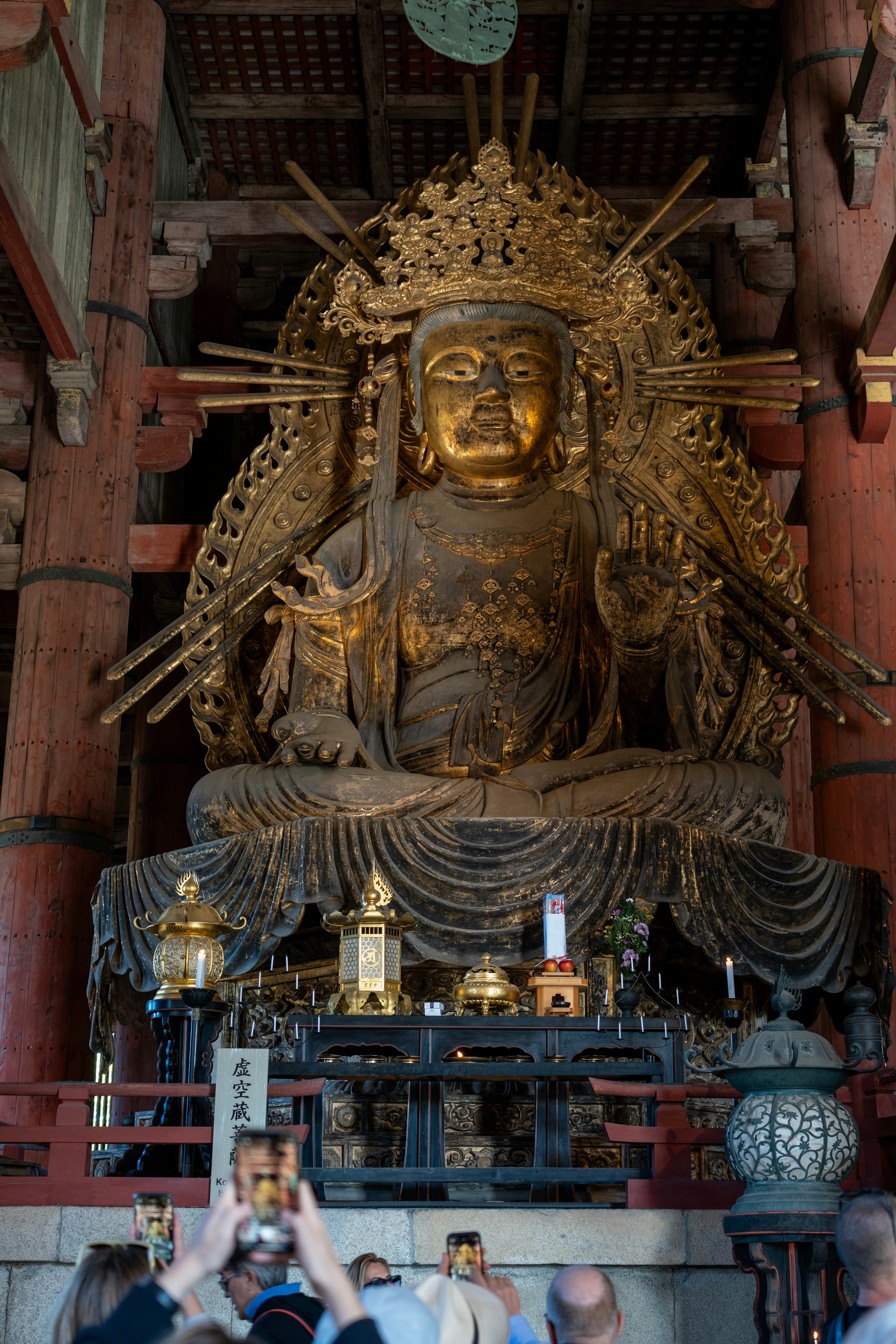 Interno di un tempio con una grande statua di Buddha dorata e visitatori