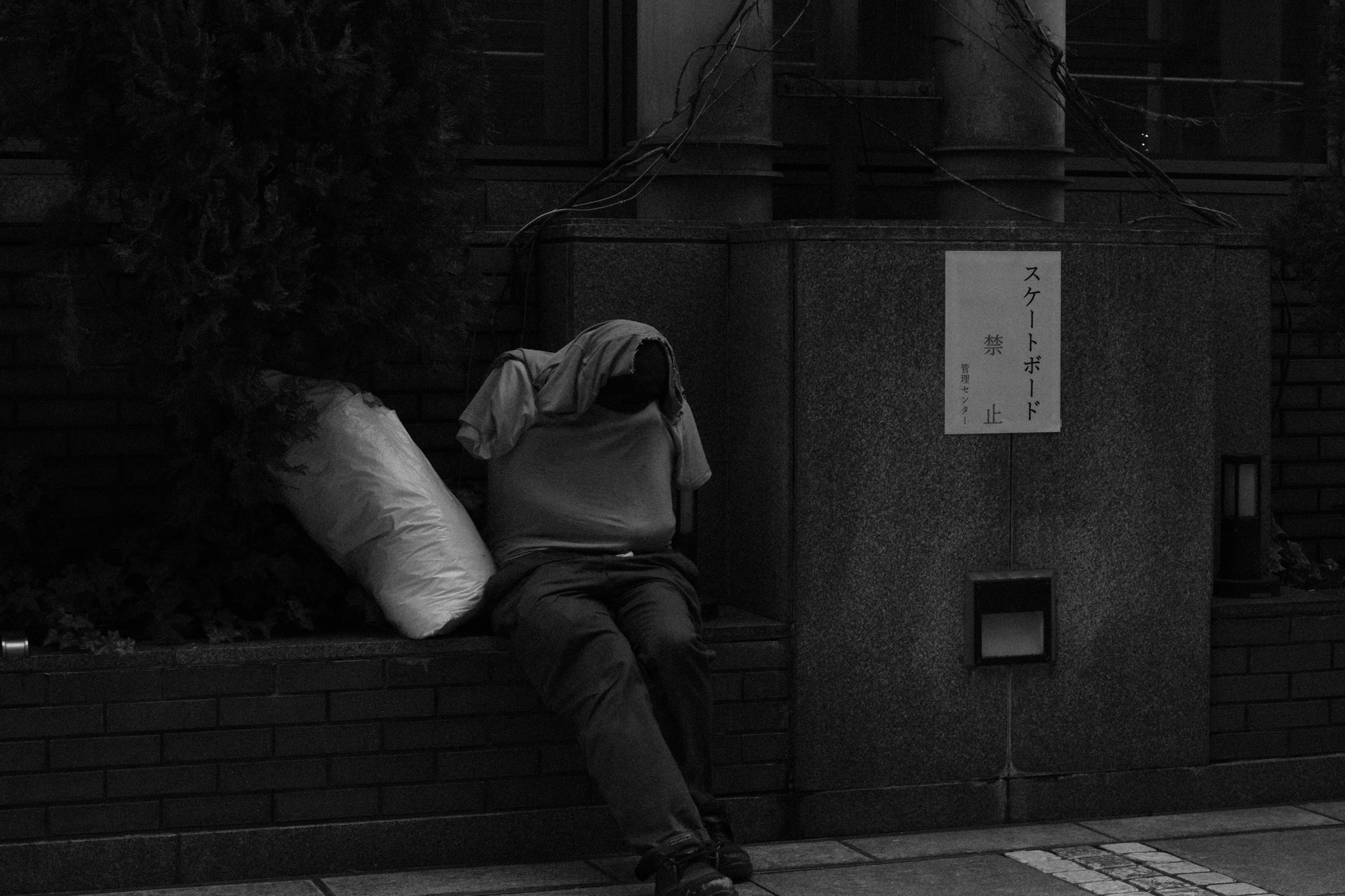 Person resting on the street with a black background