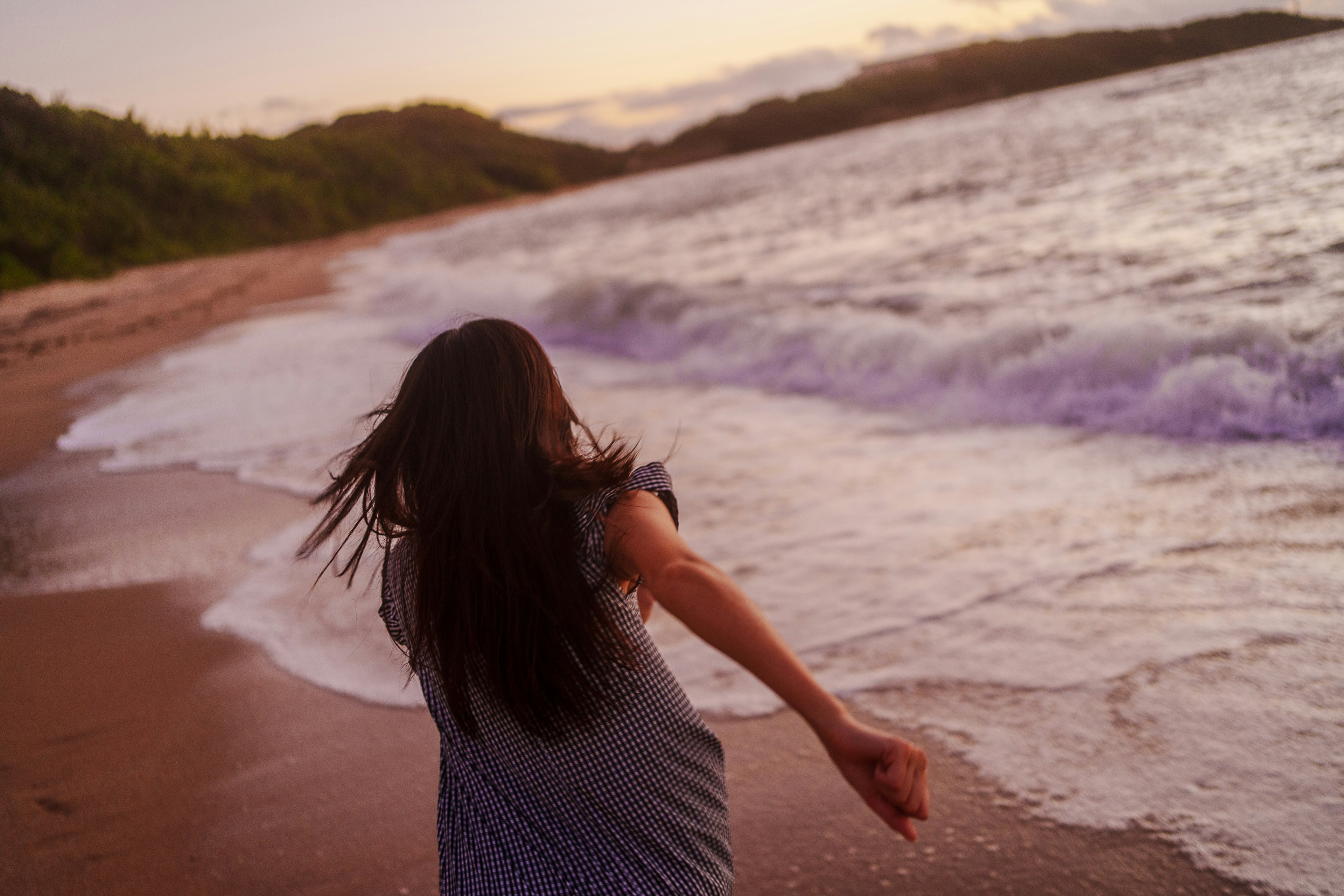 海辺で走る女性の後ろ姿と夕焼け空