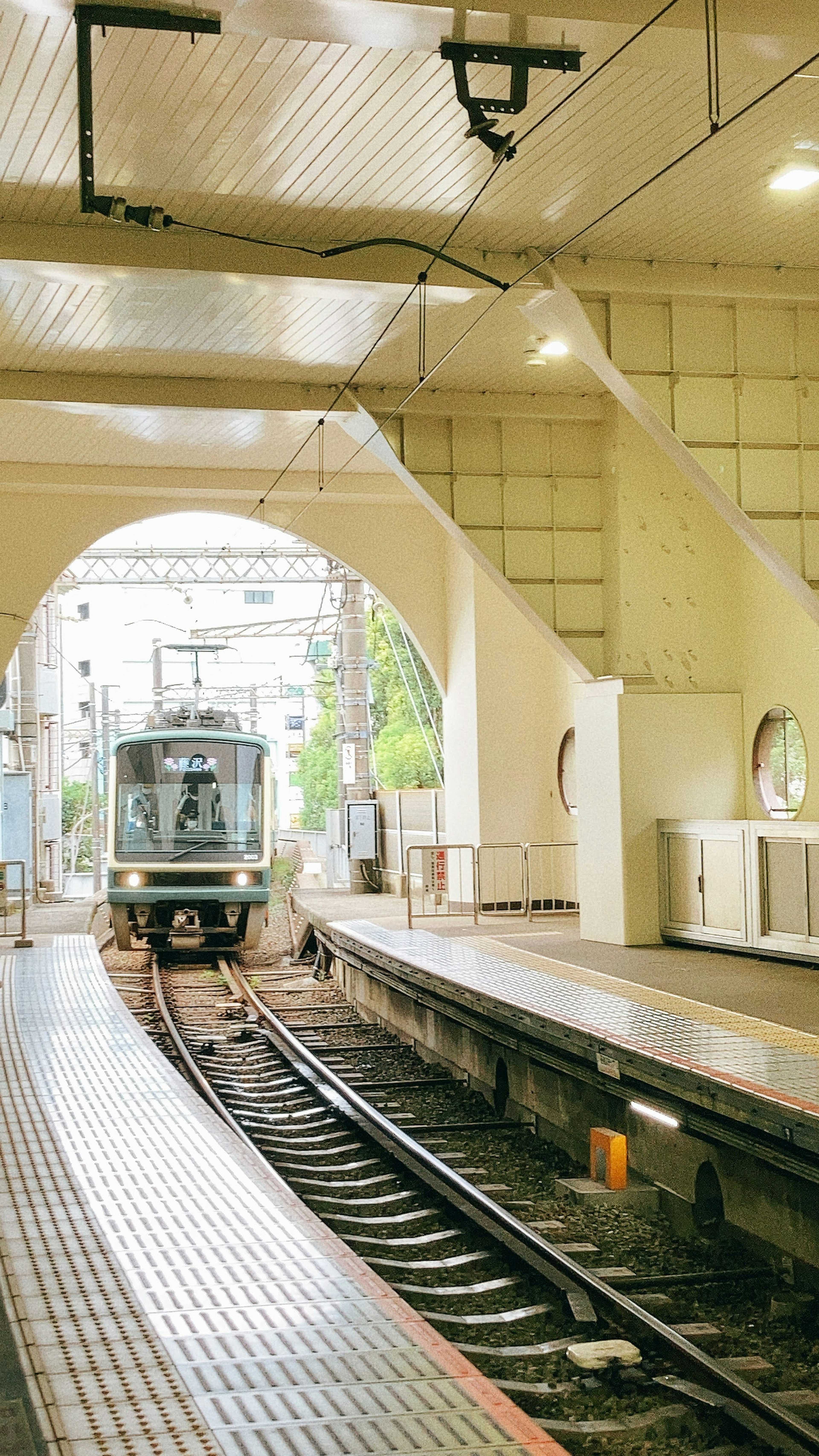 明るい駅のプラットフォームに停車中の列車と白い壁