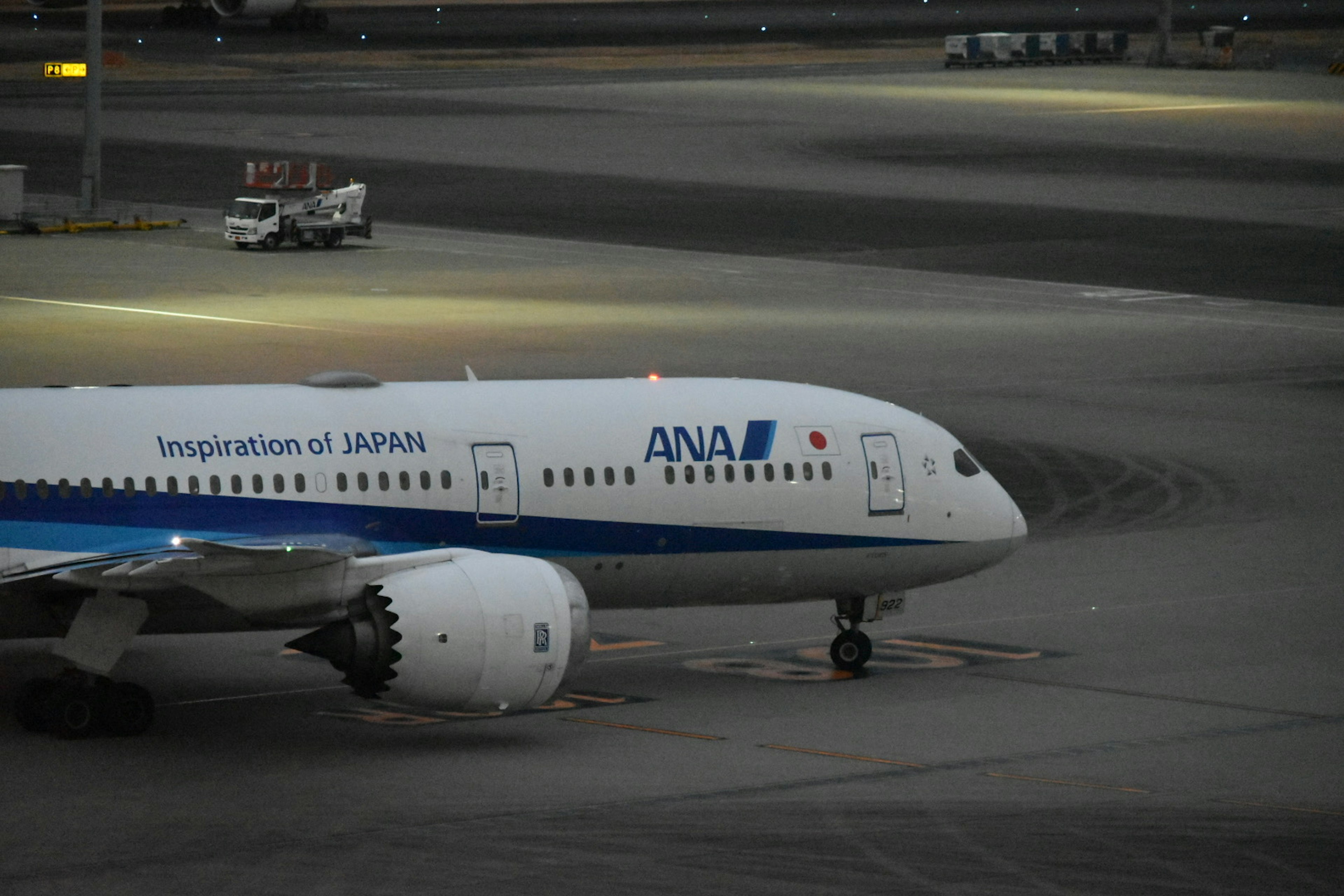 Boeing 787 de ANA estacionado en la pista en un entorno nocturno