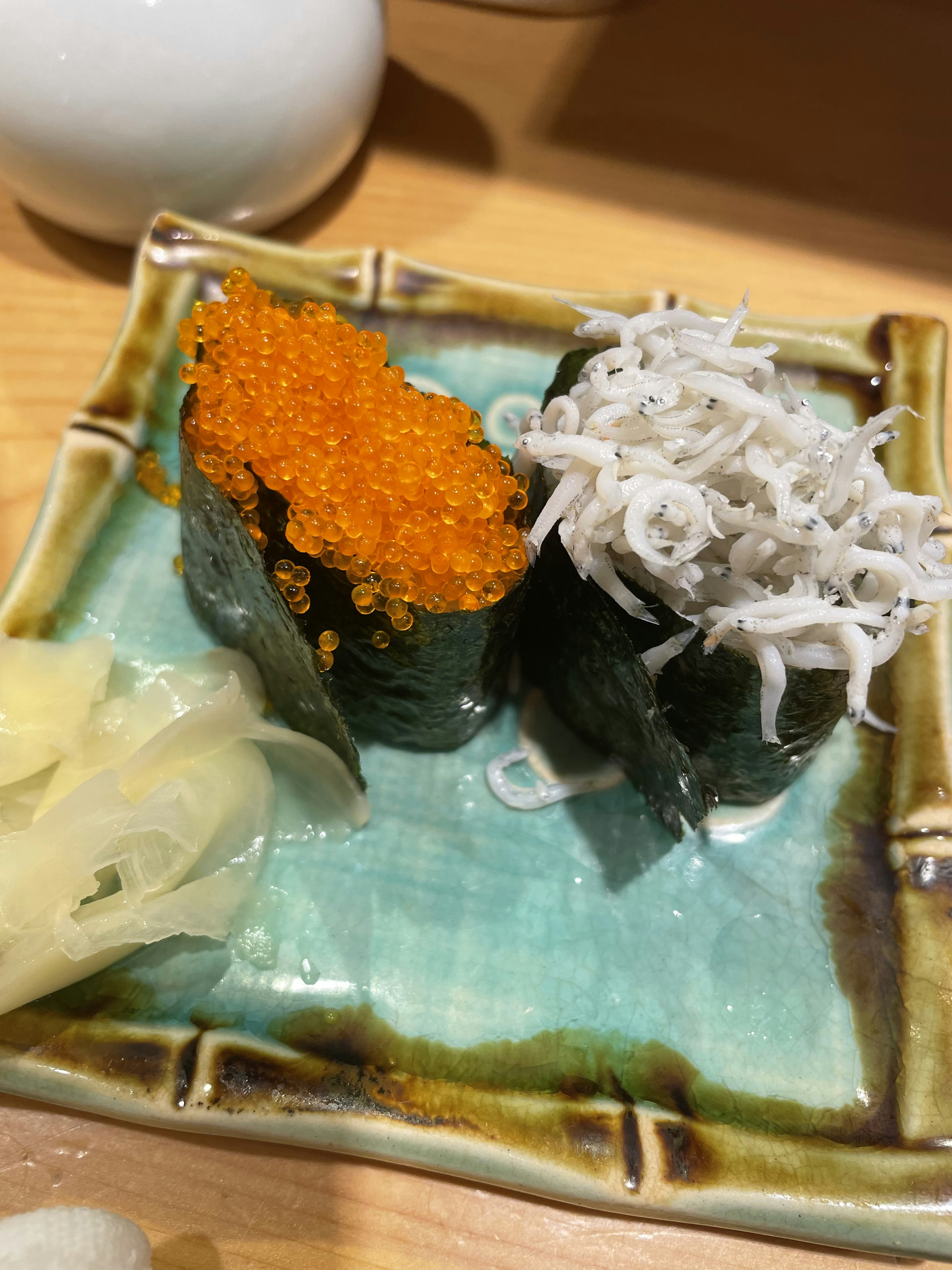 Sushi con ikura arancione vivace e shirasu bianco servito su un piatto verde