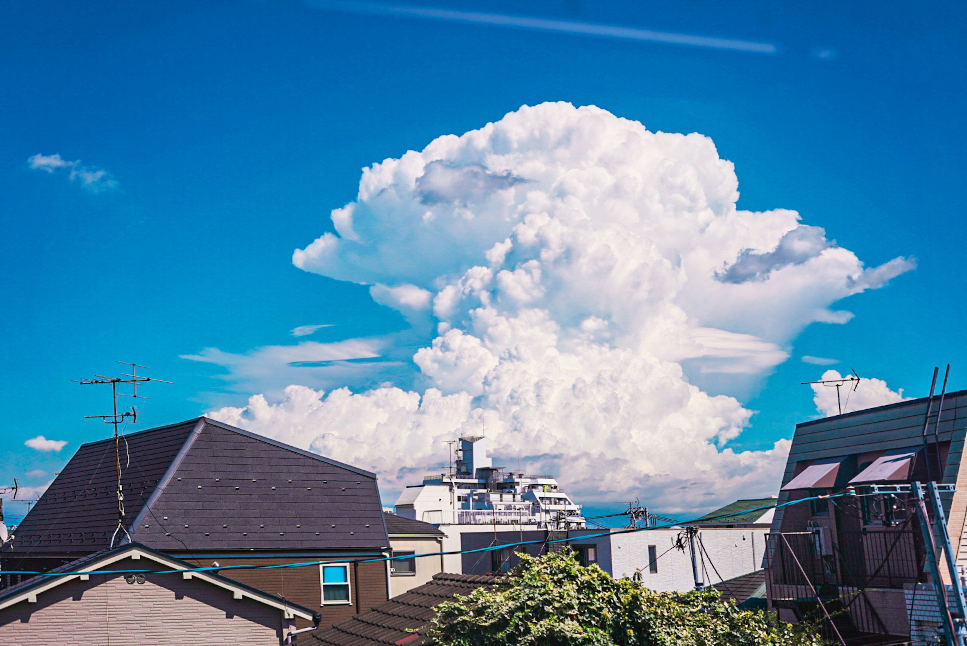 青空に浮かぶ大きな白い雲と住宅街の風景