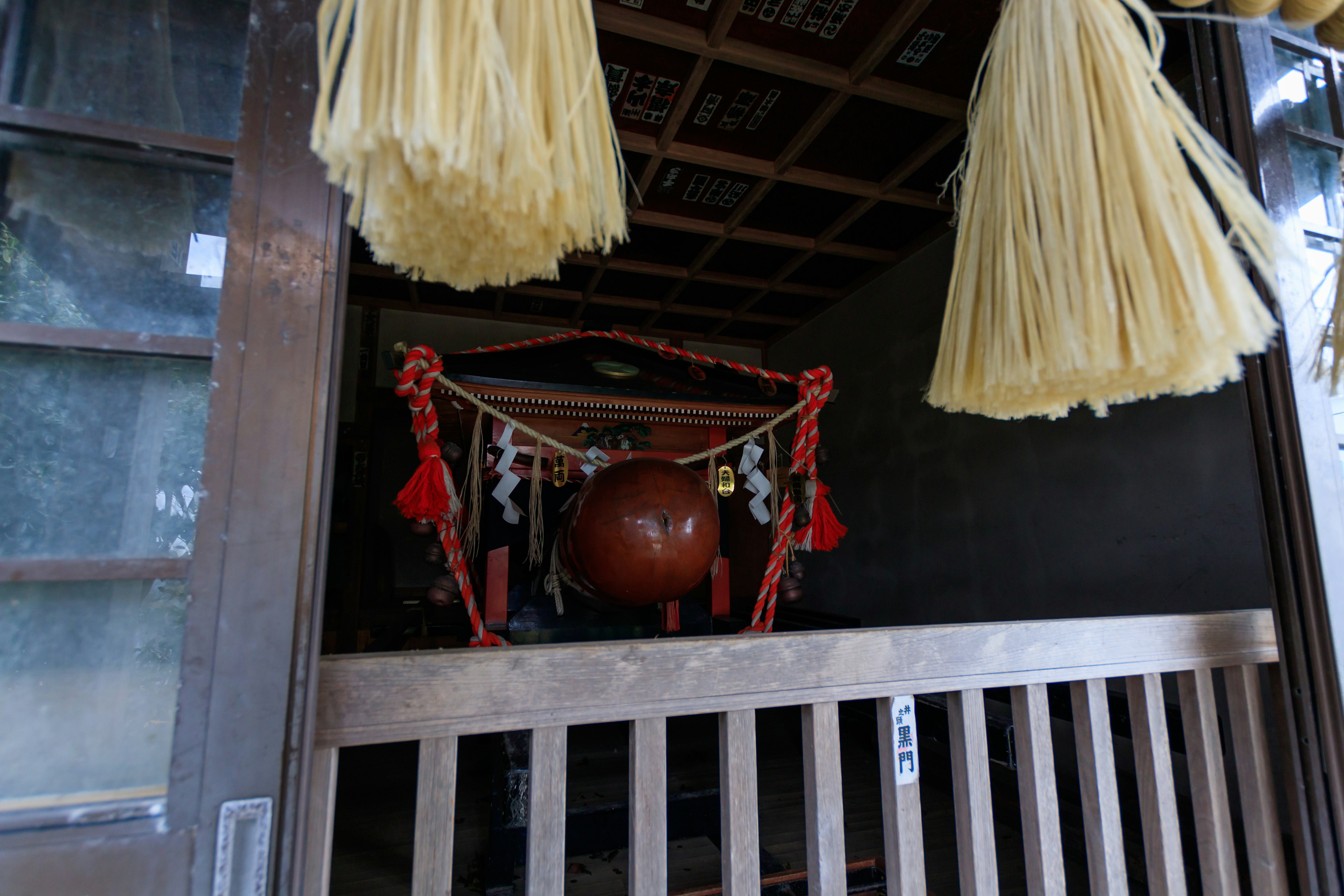 神社の入り口にある装飾されたお守りと赤い球体が見える