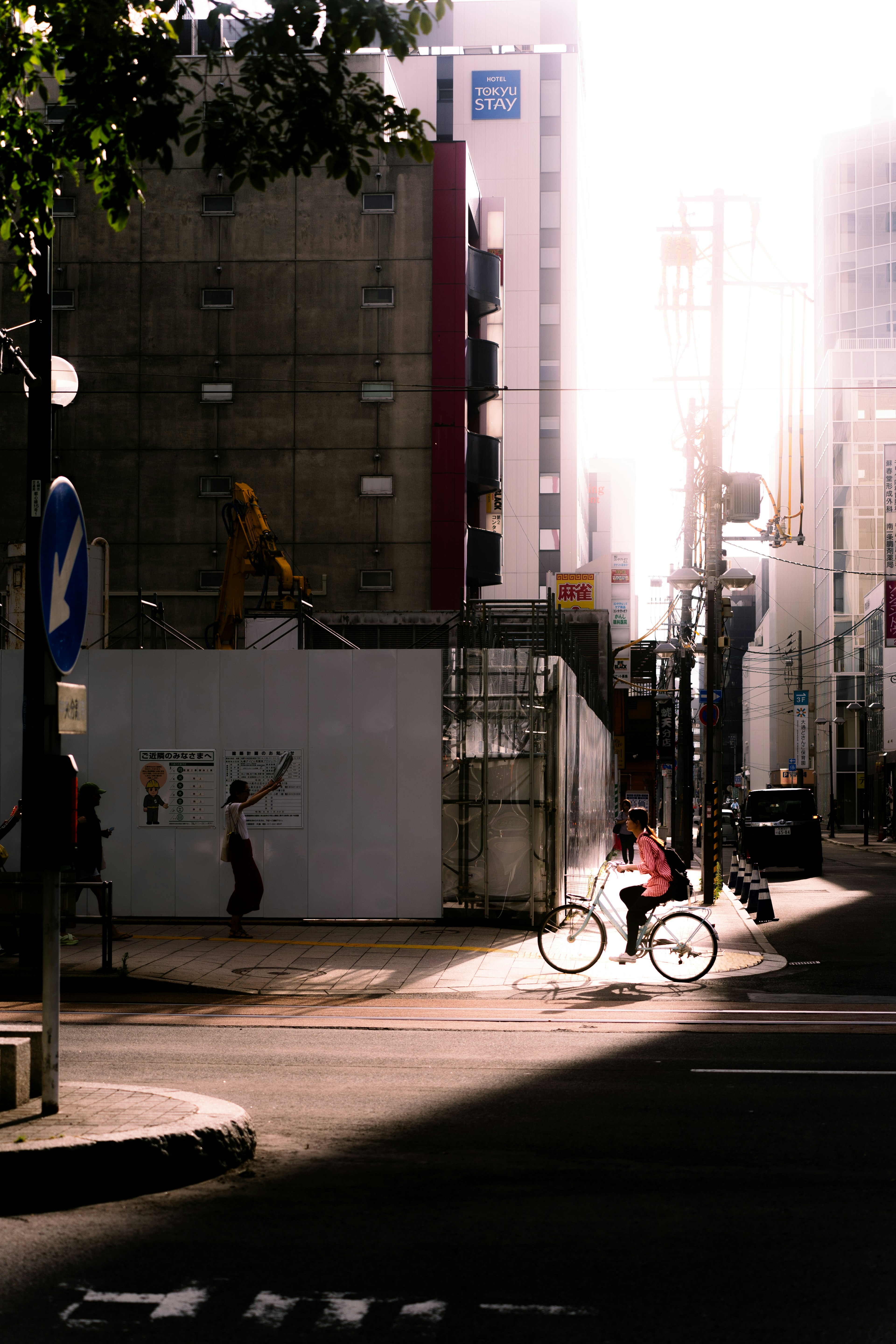 明るい街角で自転車に乗る人と建設現場の風景