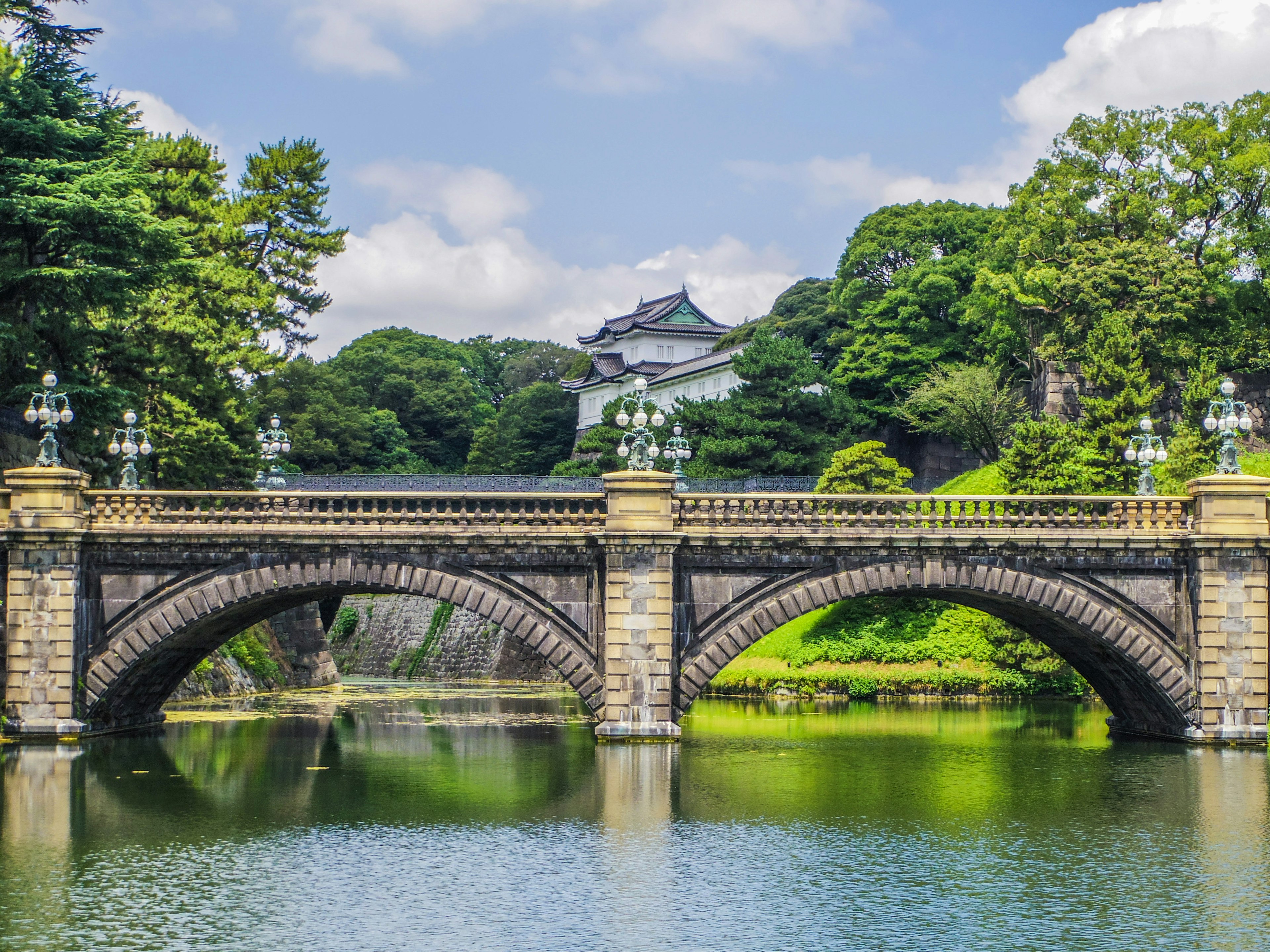 美しい石造りの橋が静かな池に架かっている