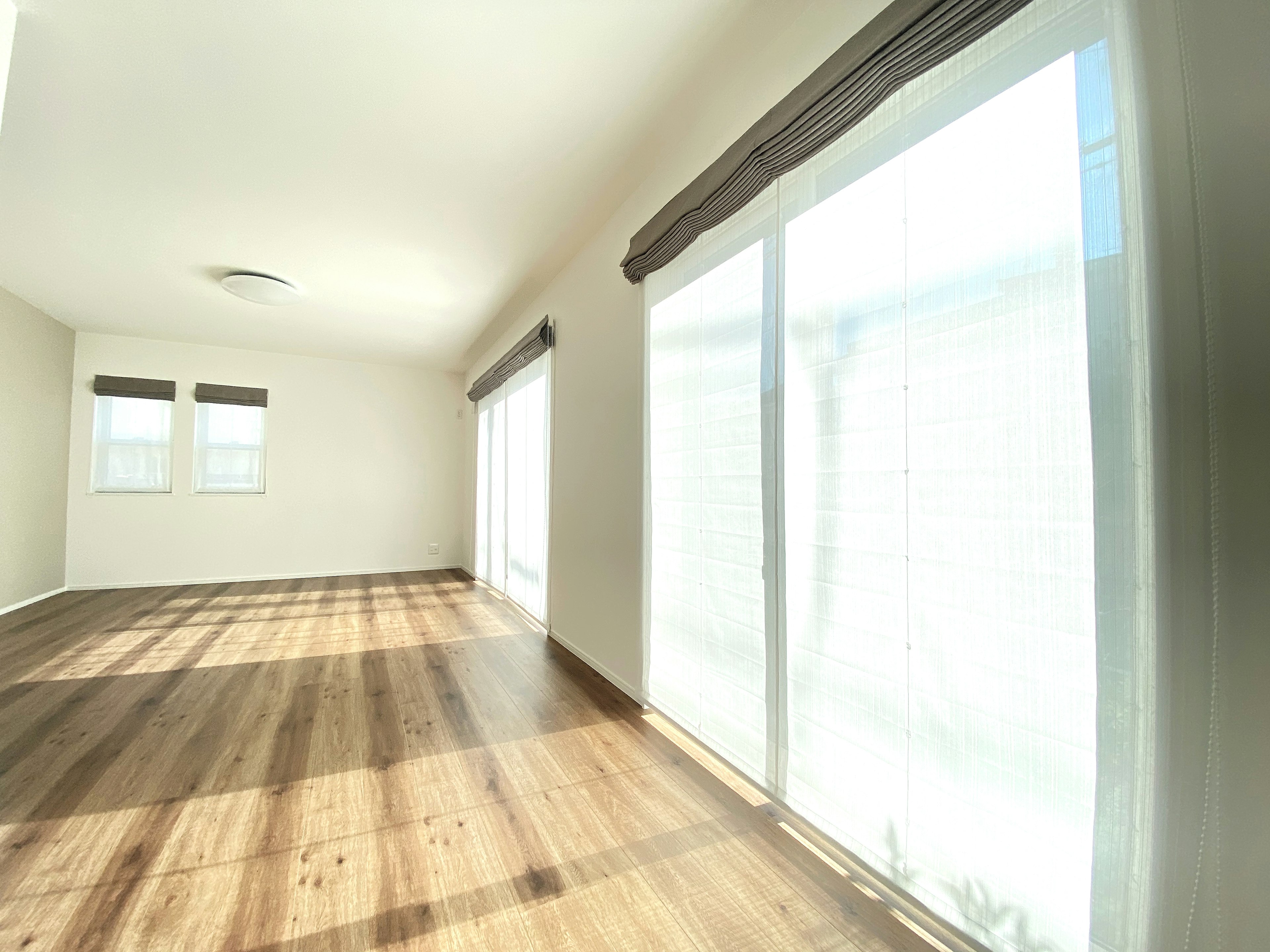 Chambre spacieuse avec un sol en bois lumineux et de grandes fenêtres