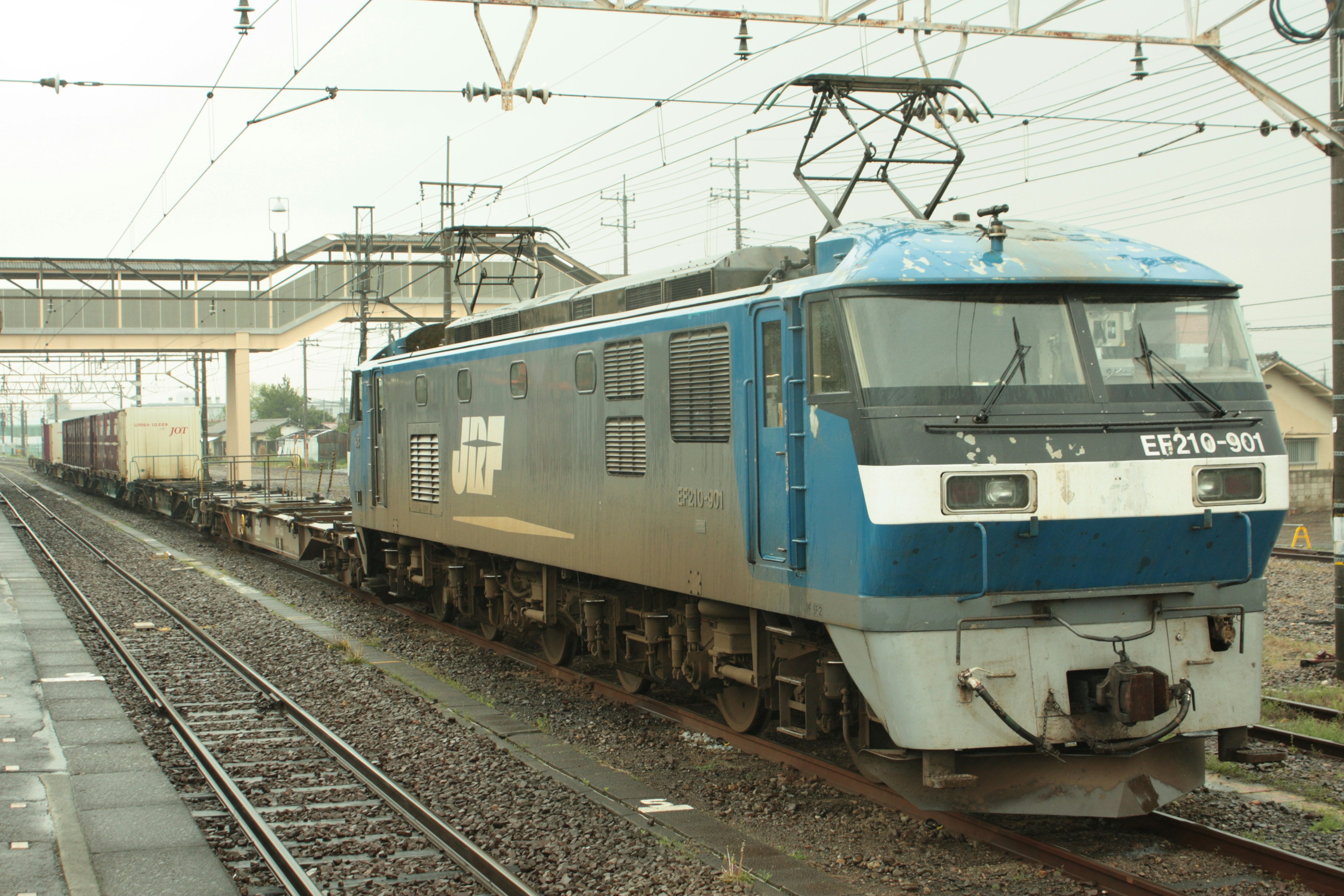 Une locomotive bleue tirant un train de marchandises sous la pluie