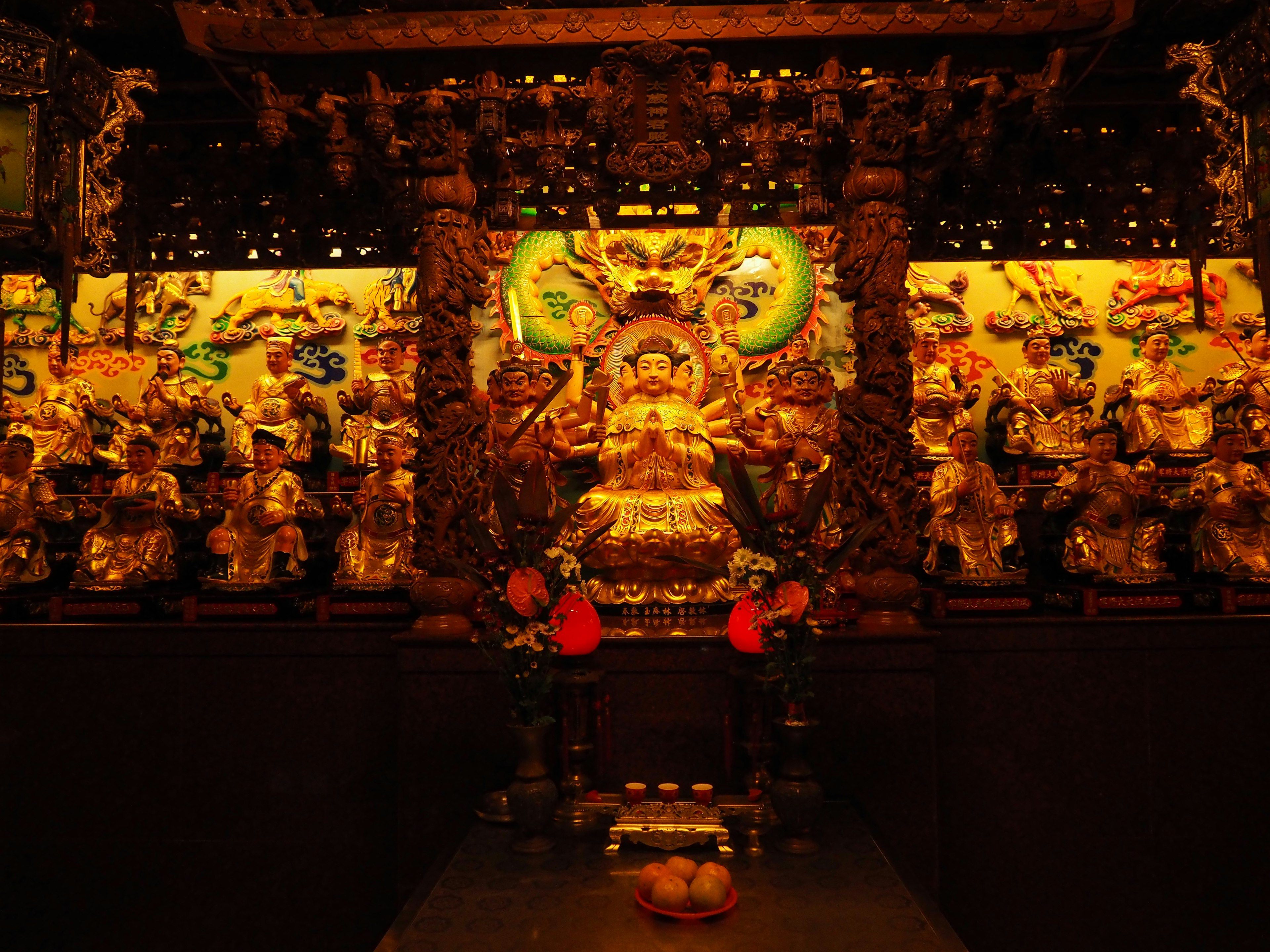 Una vibrante estatua de Buda en el centro rodeada de tallas coloridas en el interior de un templo