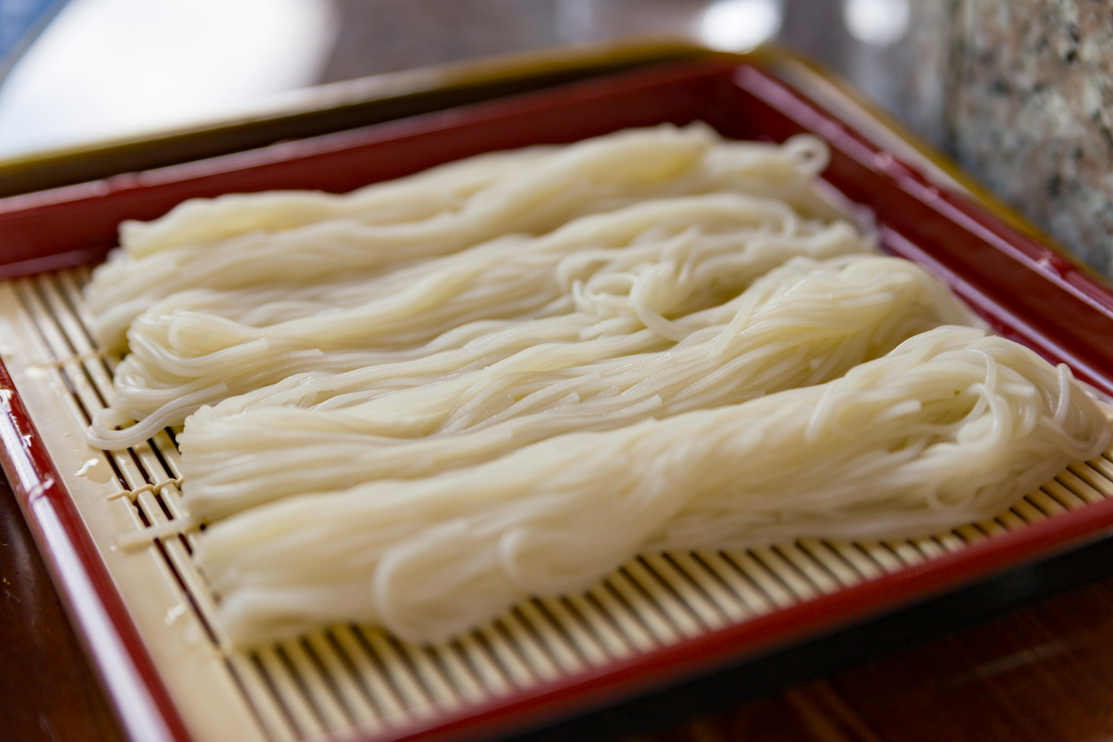 Thin white noodles arranged on a bamboo tray