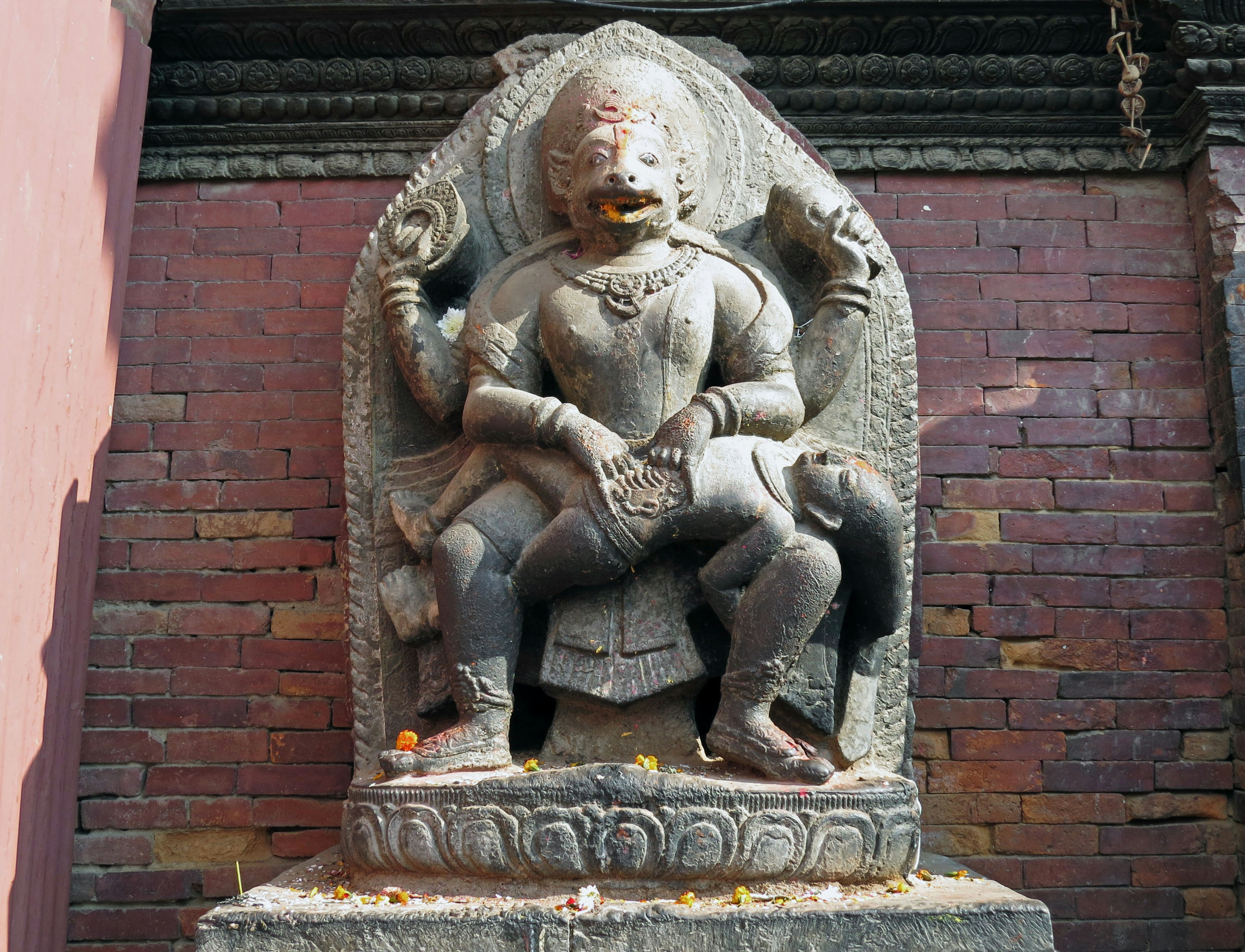 Stone sculpture of a deity seated on a throne