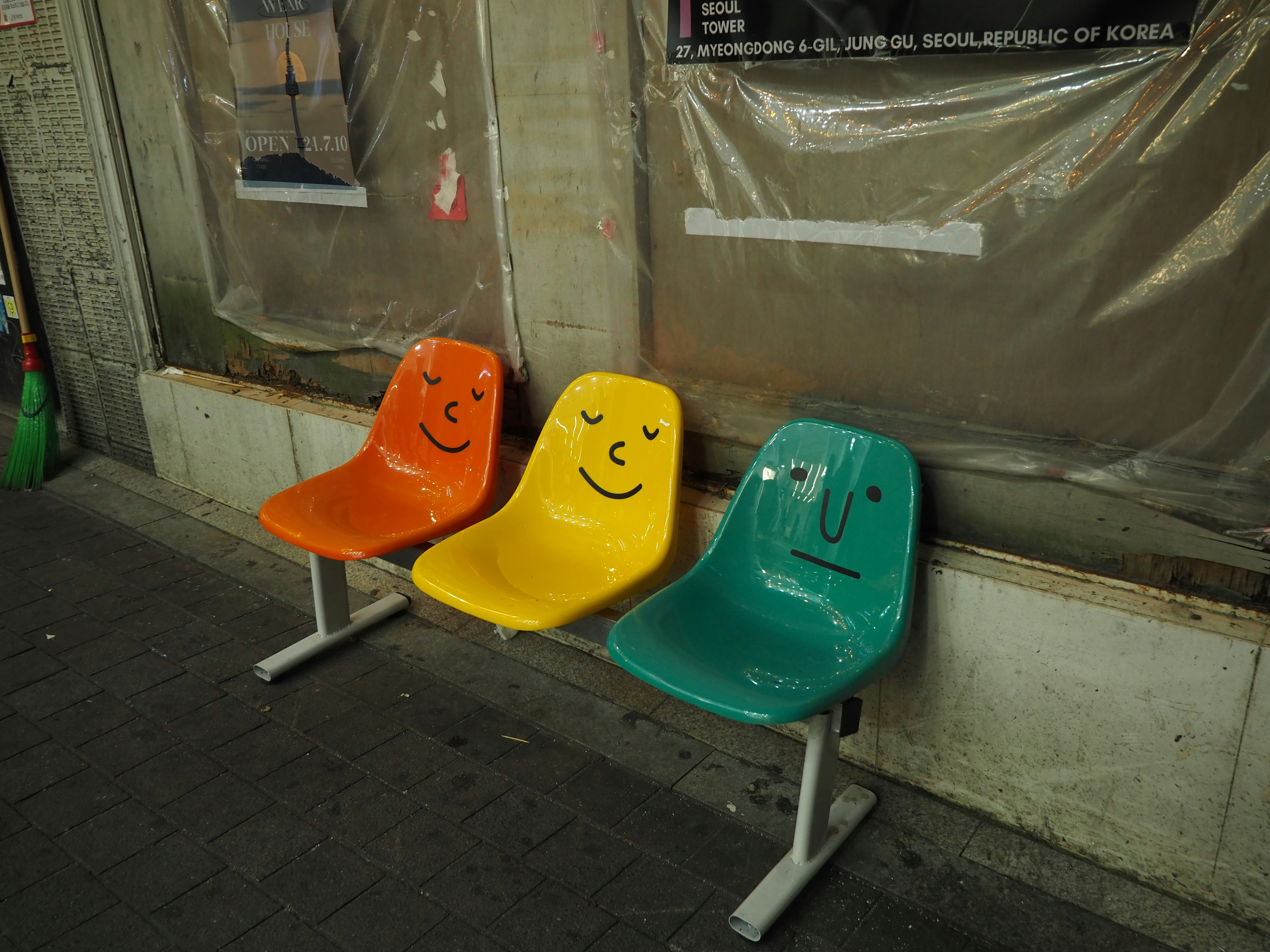 Sillas coloridas con caras sonrientes y neutrales dispuestas en fila