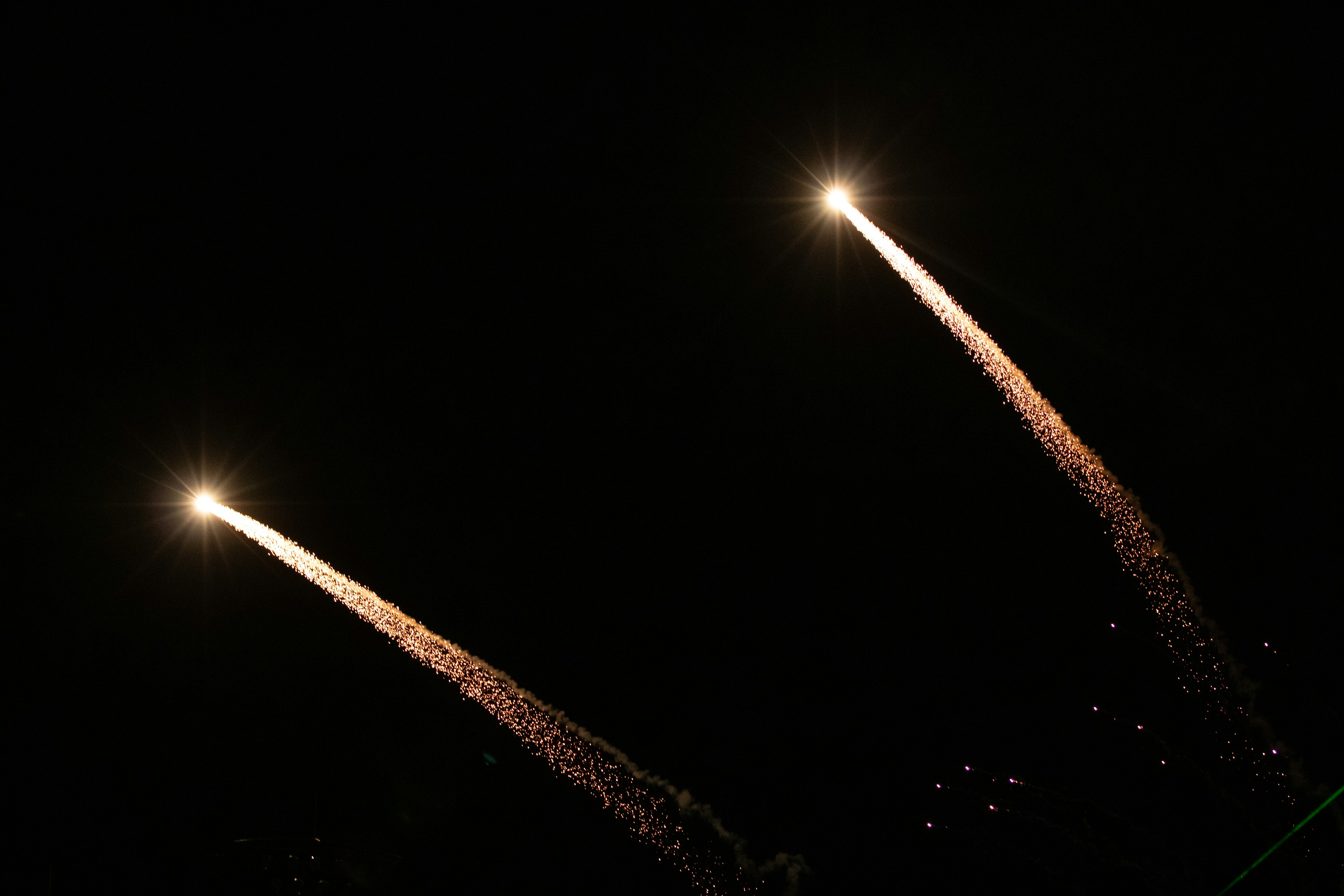 Dos cohetes ascendiendo en el cielo nocturno dejando estelas de chispas