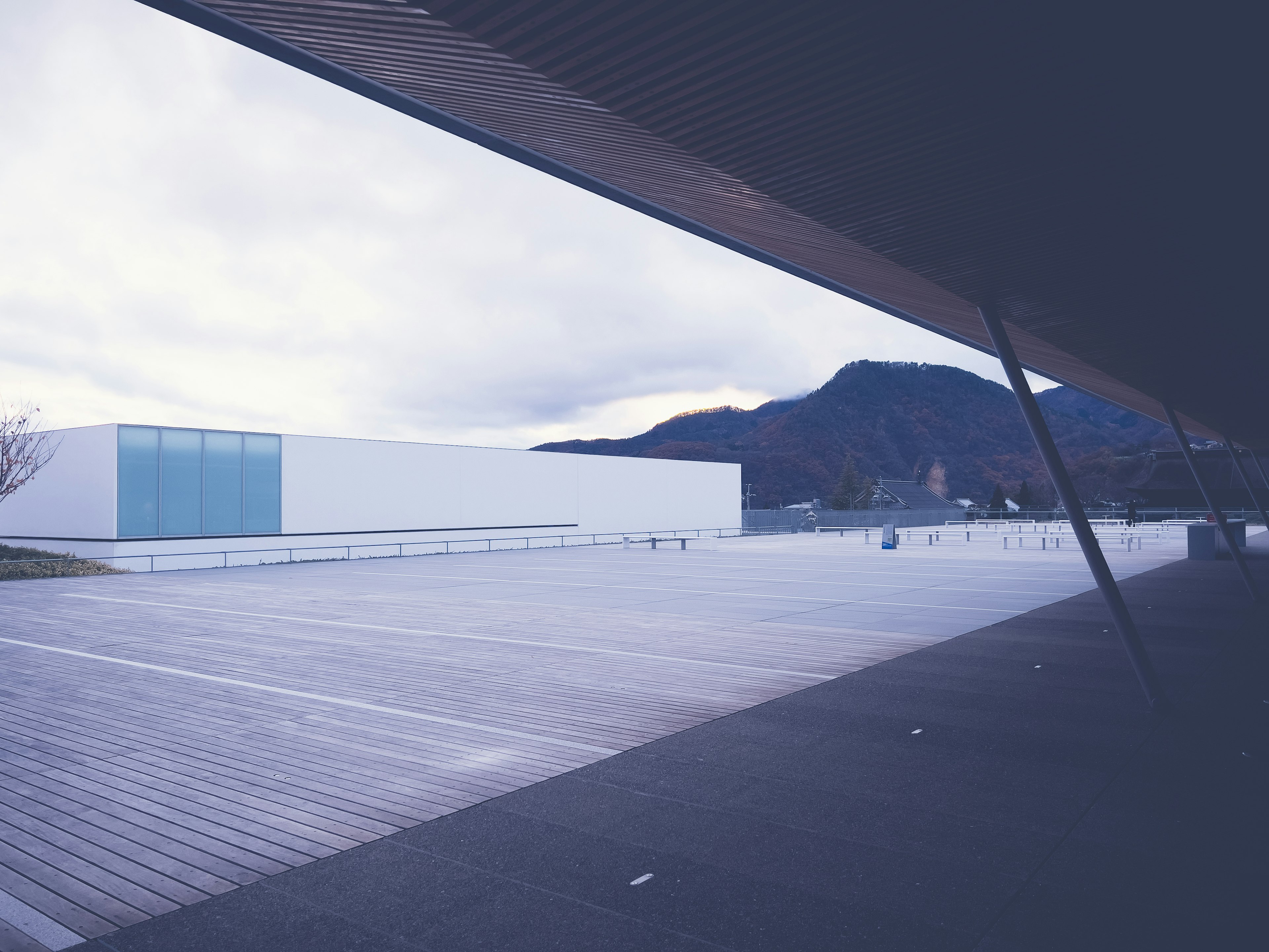 Edificio moderno con sfondo montano e ampia terrazza in legno