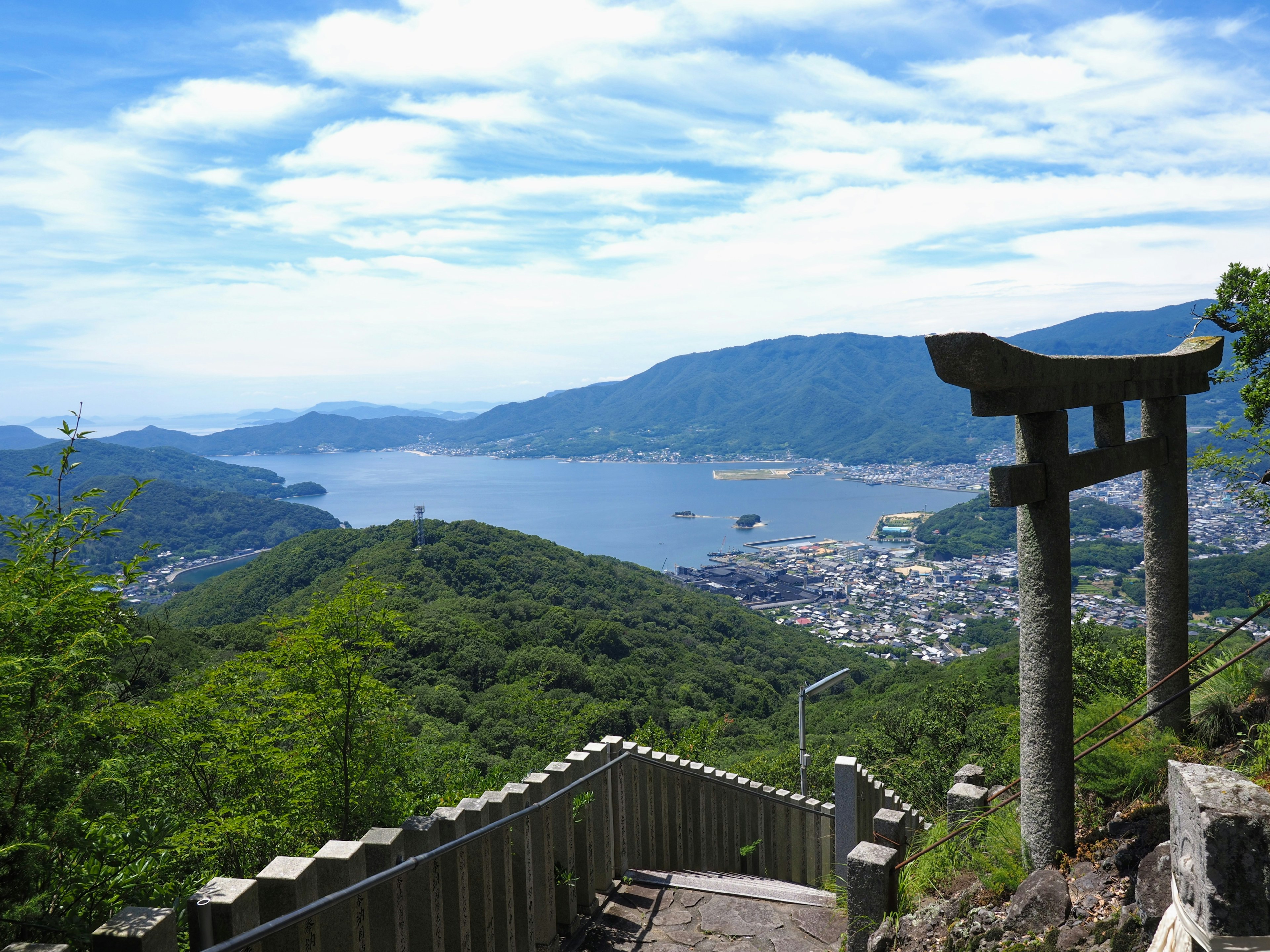 Vista panoramica di montagna con un torii che sovrasta il mare blu e il cielo