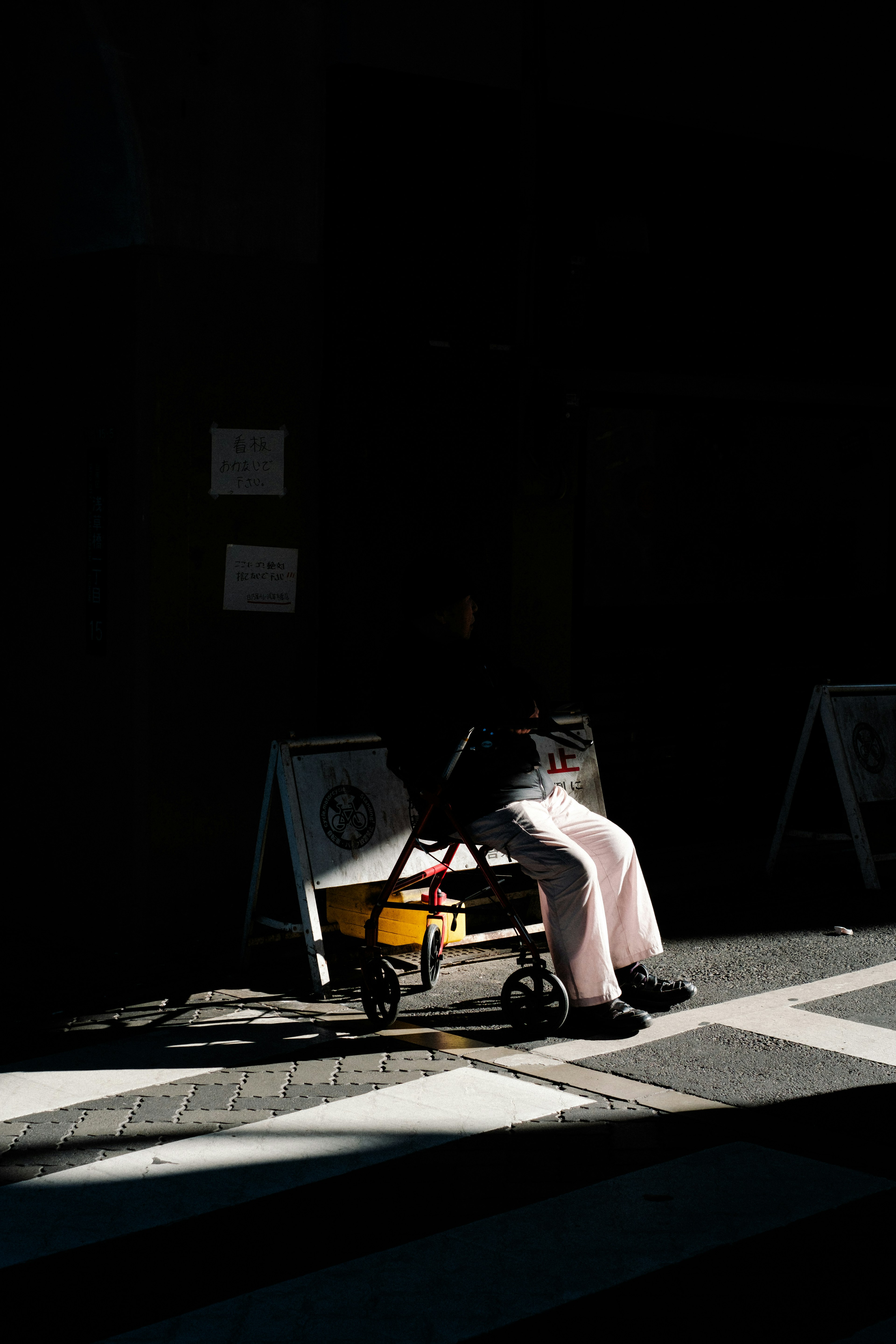 Silhouette of a person sitting with a cart against a dark background