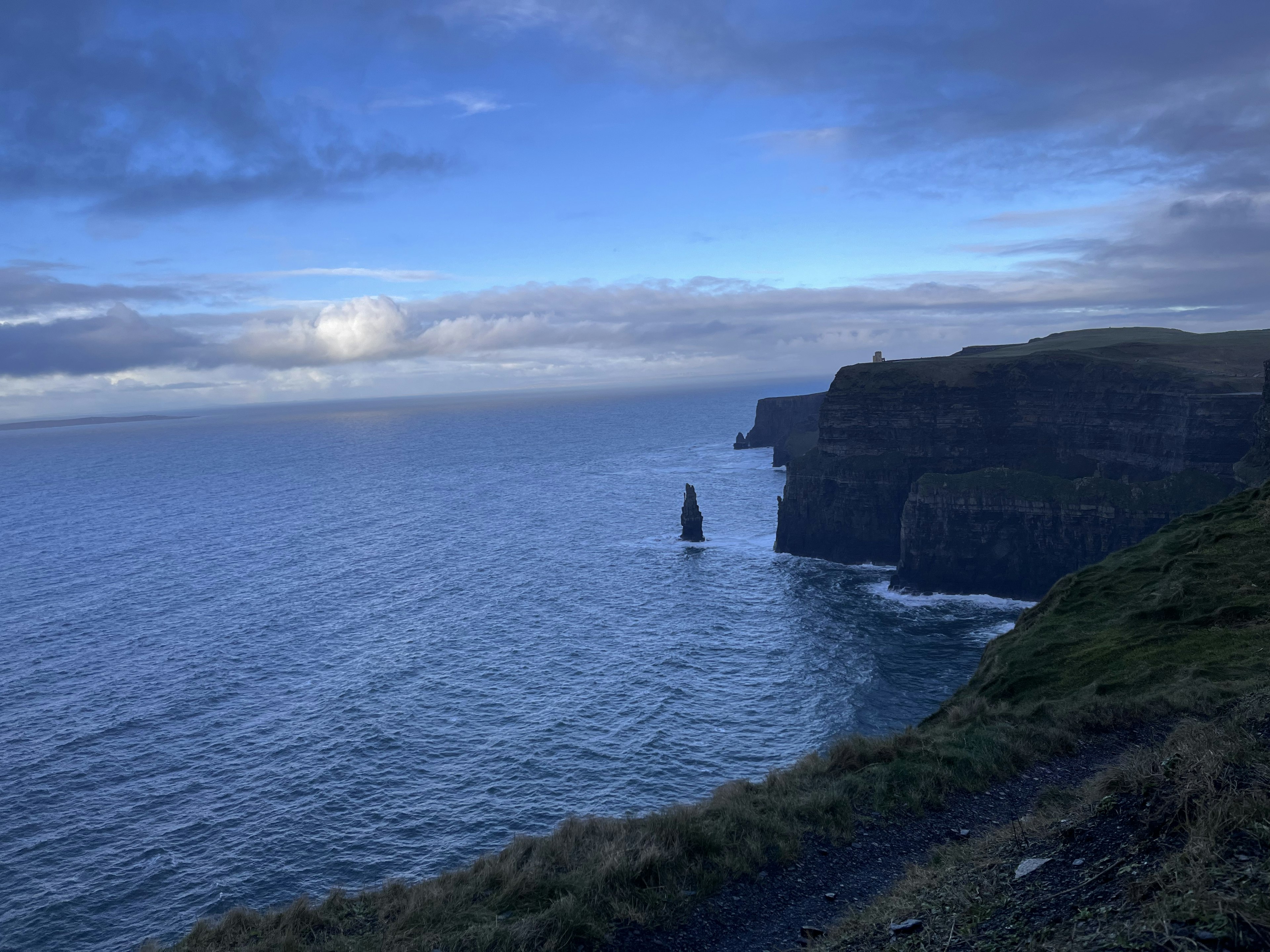 Isolated rock standing amidst the vast sea and cliffs