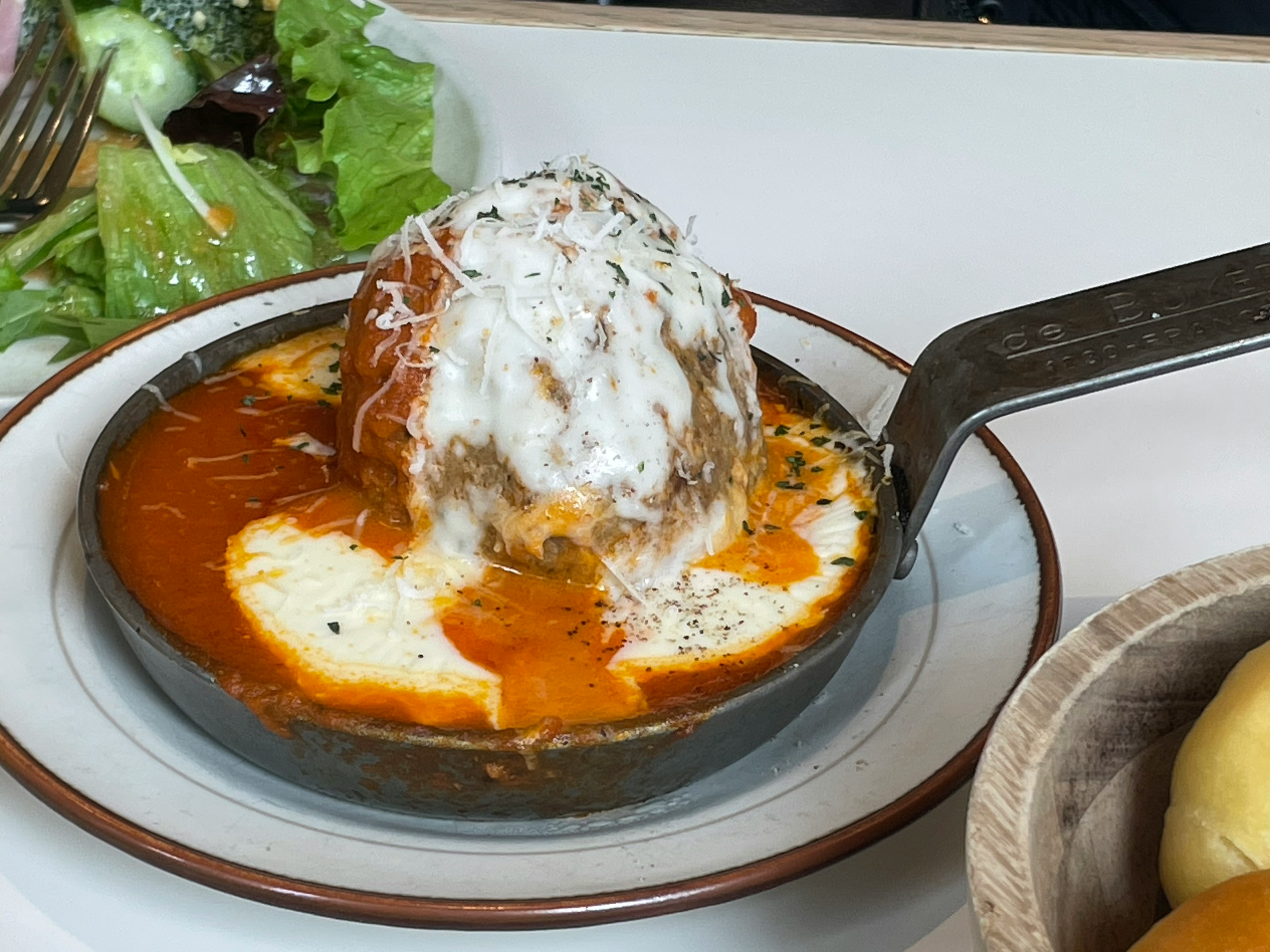 Fleischbällchen in einer Pfanne mit Sahnesauce und Kräutern serviert