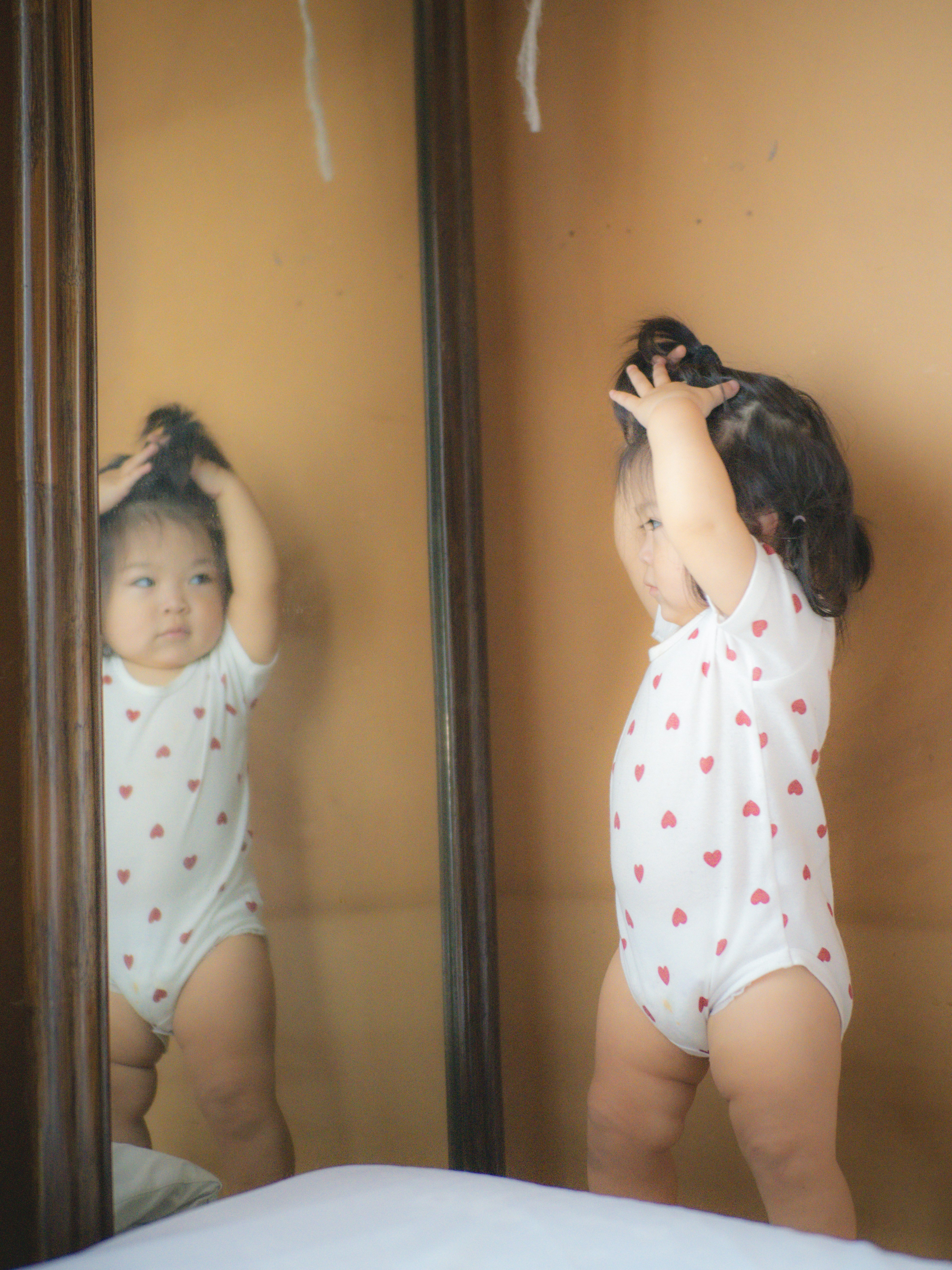 Baby playing with hair in front of a mirror