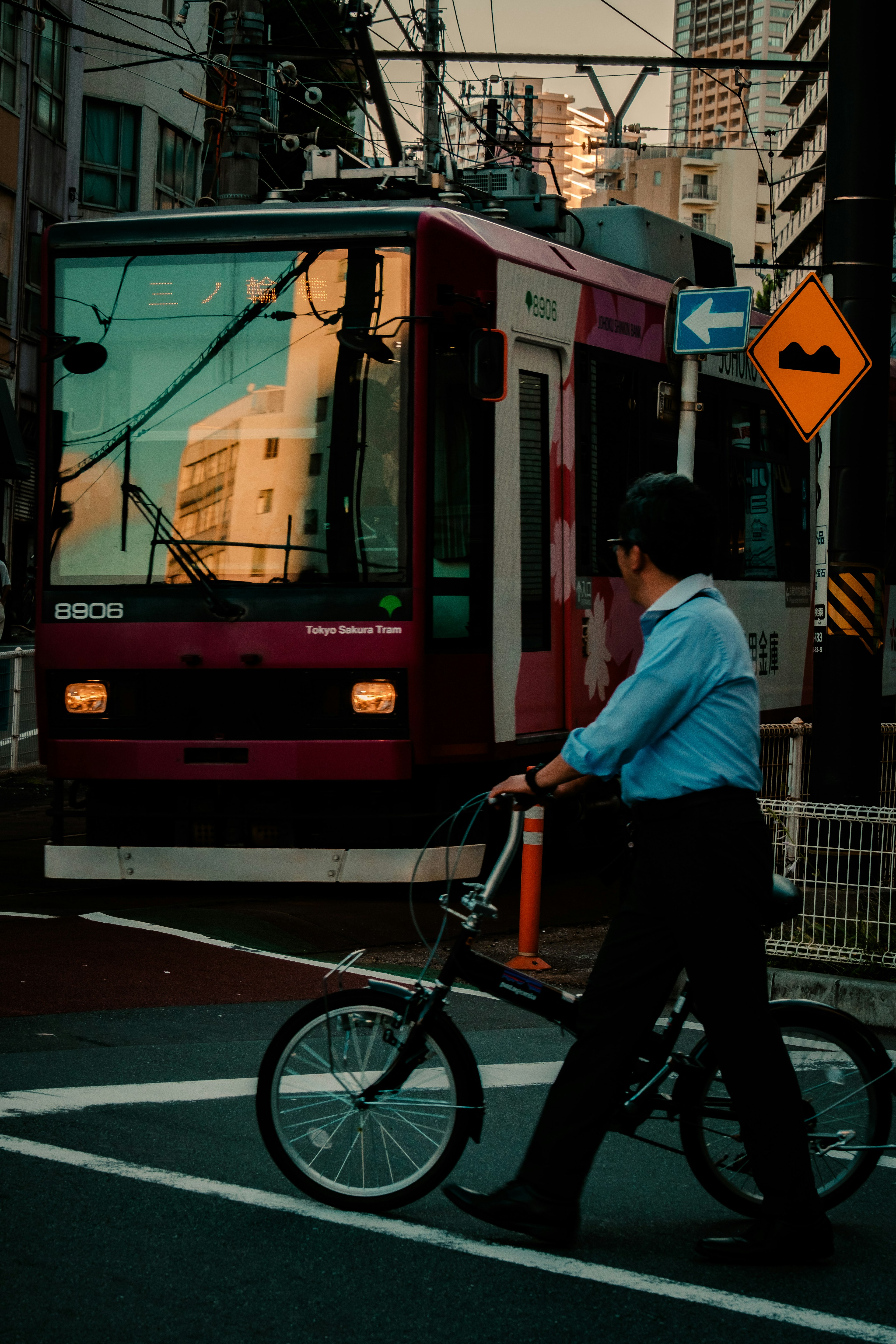 一名男子在城市中推著自行車走過一輛電車