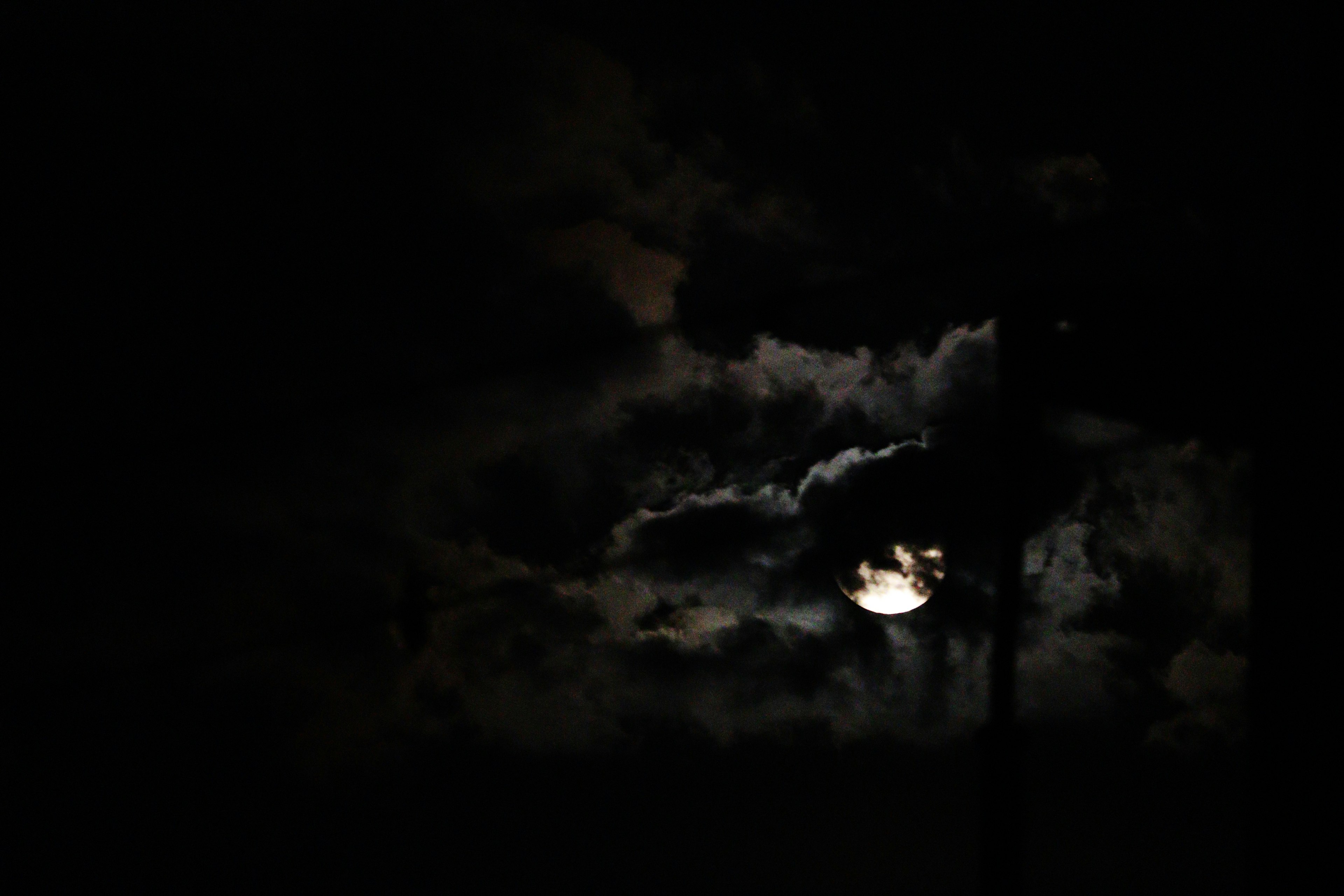 Lune partiellement obscurcie par des nuages dans un ciel sombre