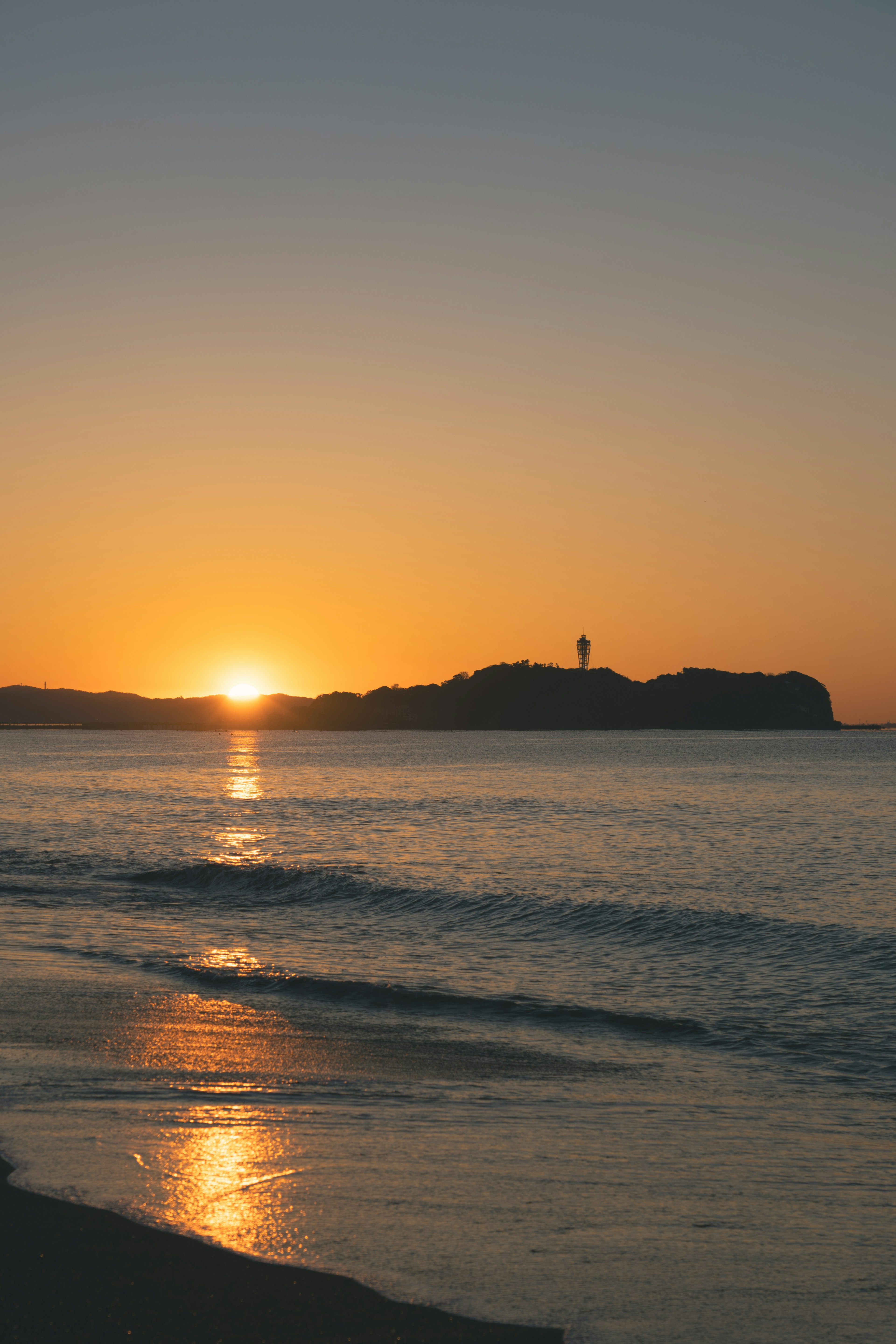 Sonnenuntergang über dem Ozean mit einem entfernten Leuchtturm