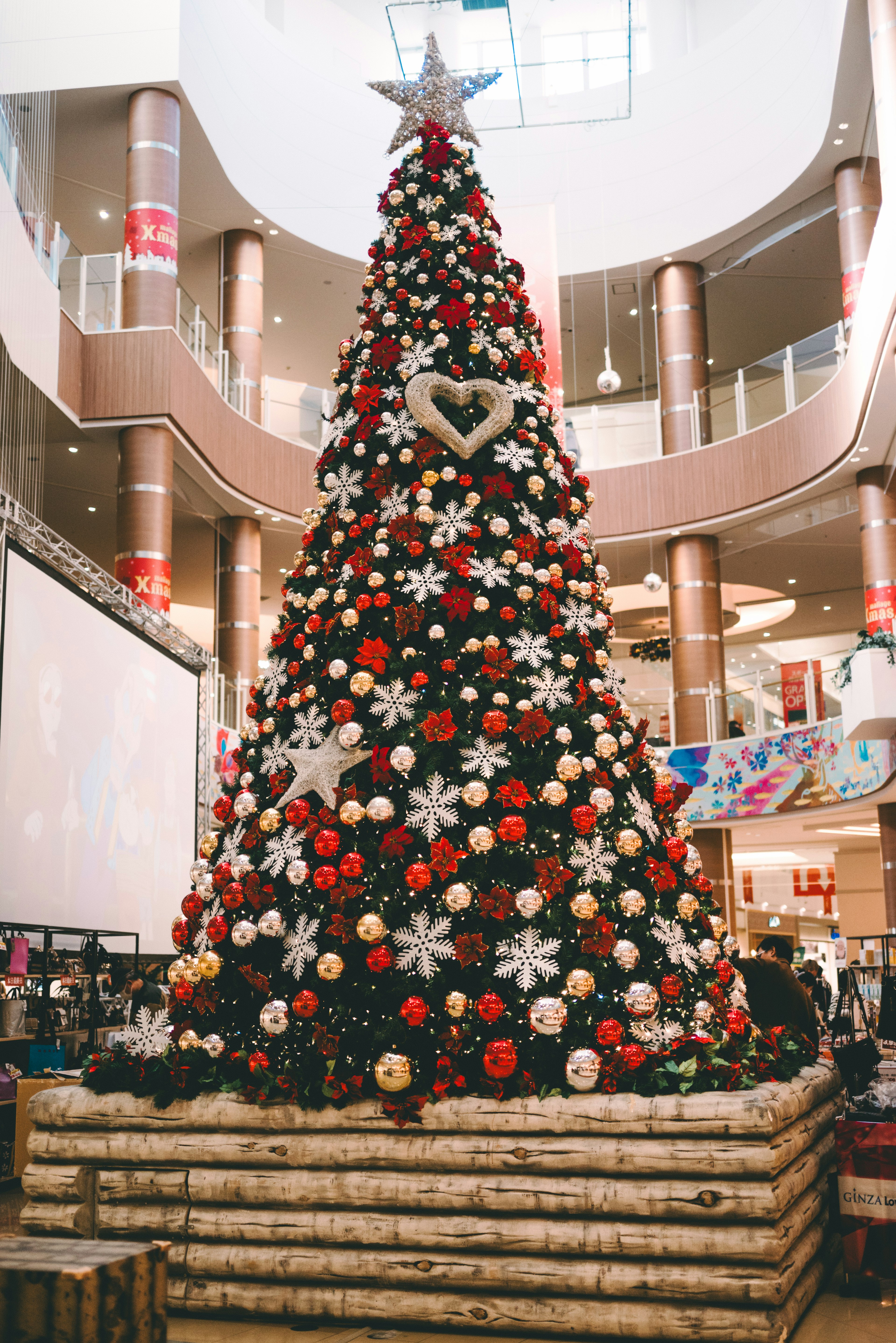 Un árbol de Navidad vibrante decorado con adornos rojos y blancos en un centro comercial