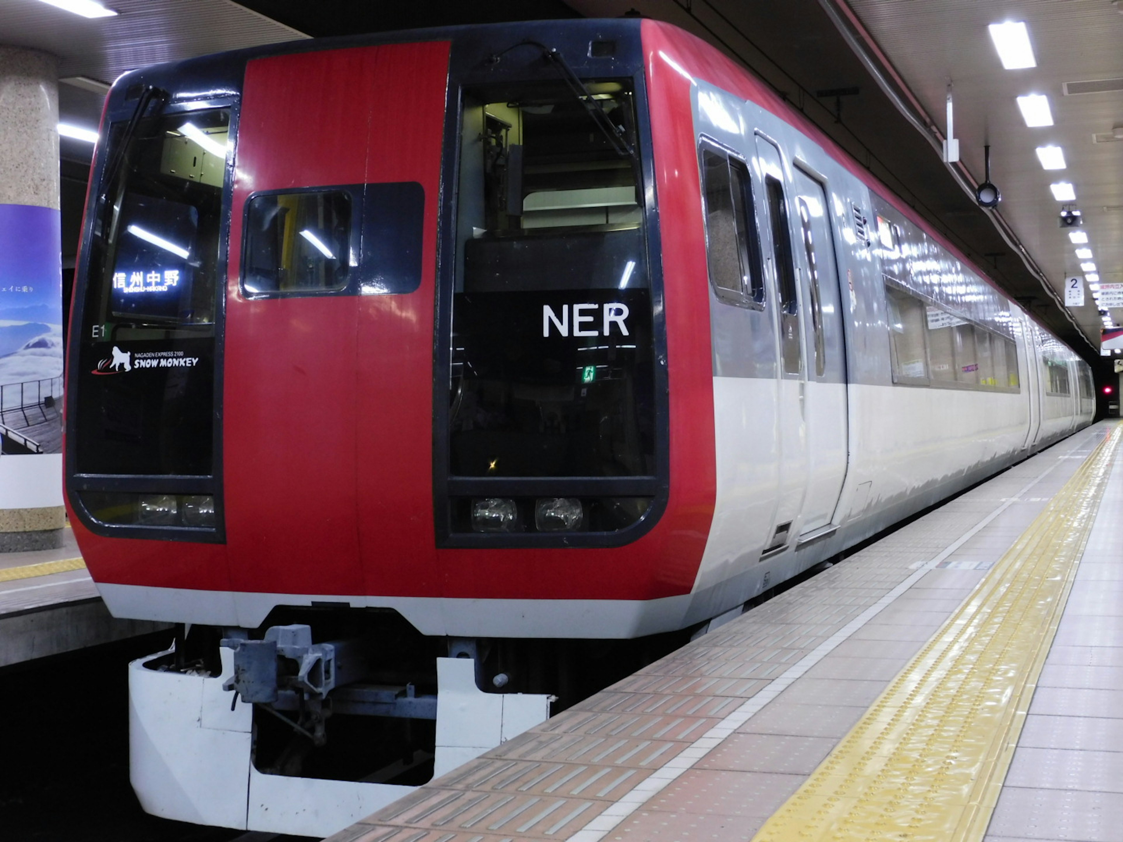 Train rouge et blanc arrêté sur le quai de la gare