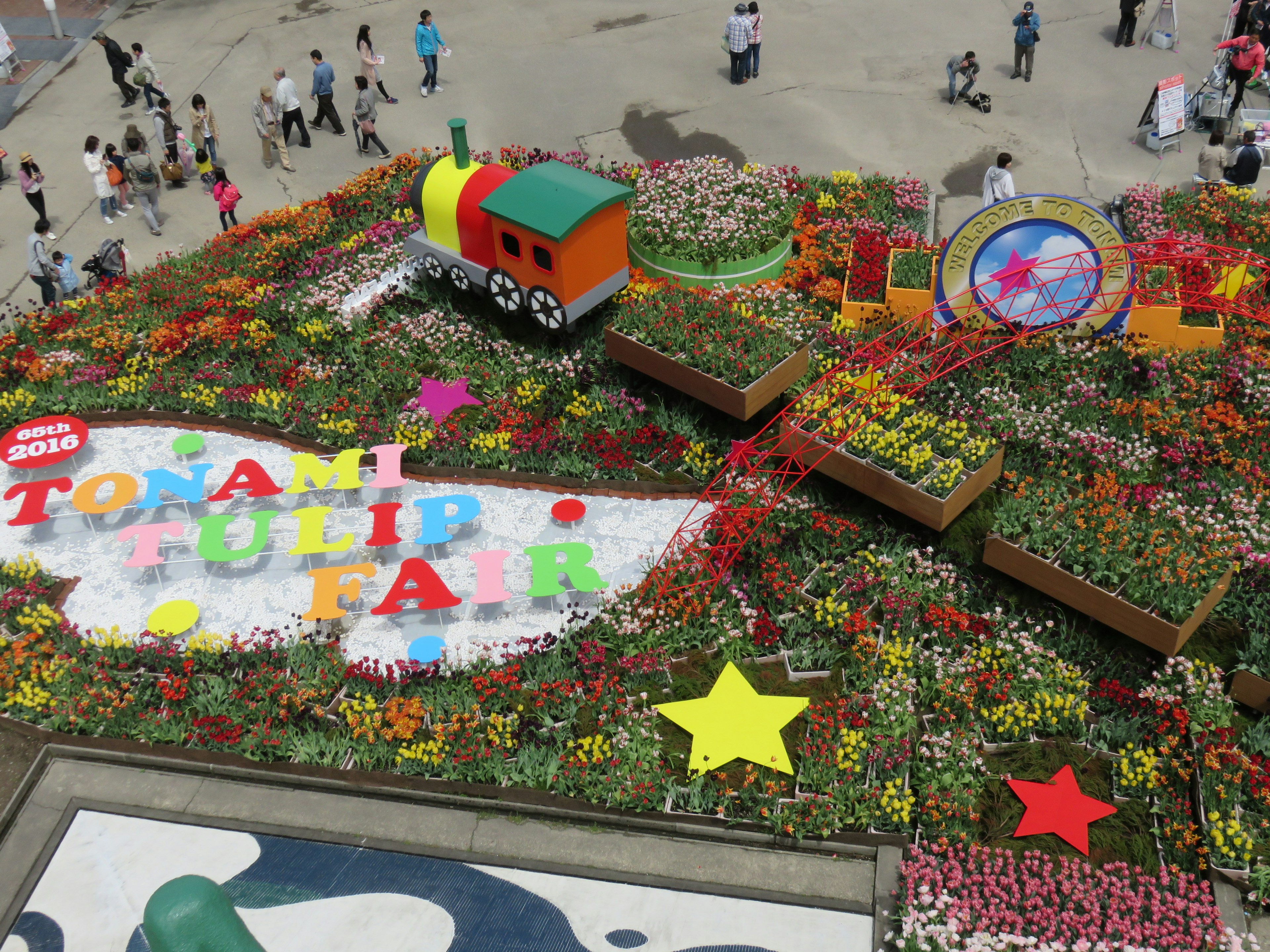 Bunte Blumenanordnung mit einem Zug und einem großen Schild auf einer Messe