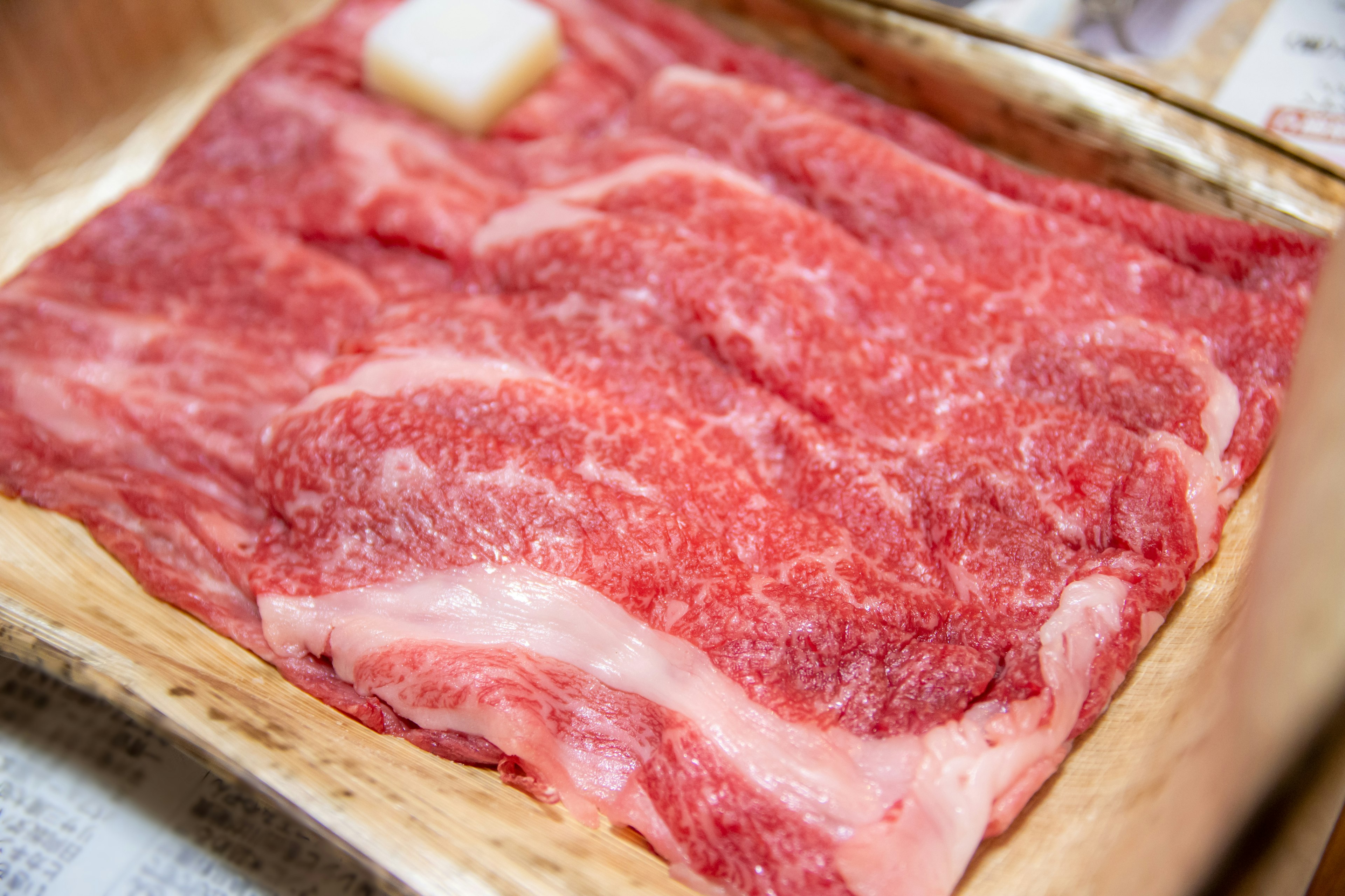 Irisan daging Wagyu yang bermarmer indah disajikan di atas piring kayu