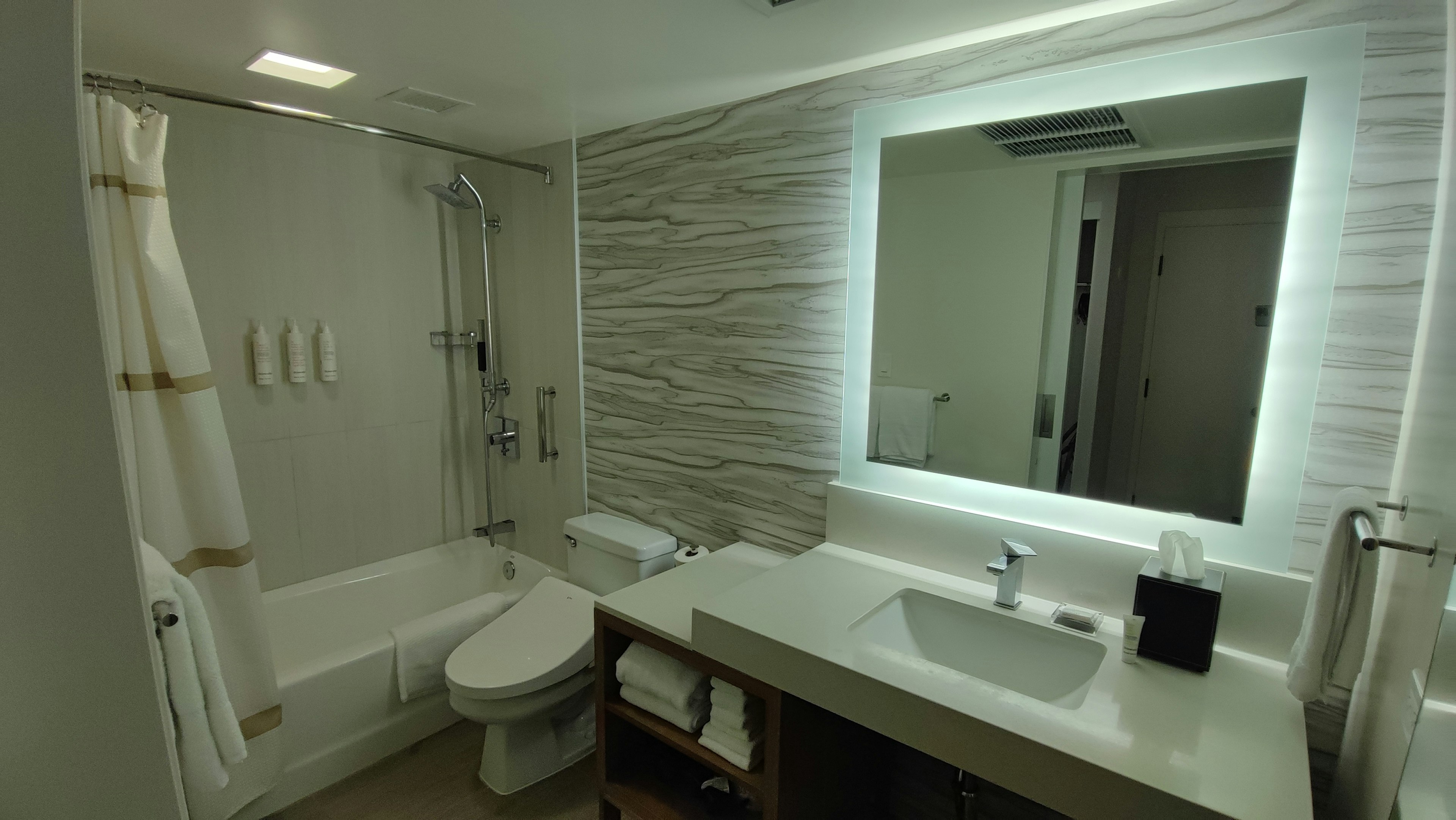 Bright bathroom with white tiles featuring a shower and toilet