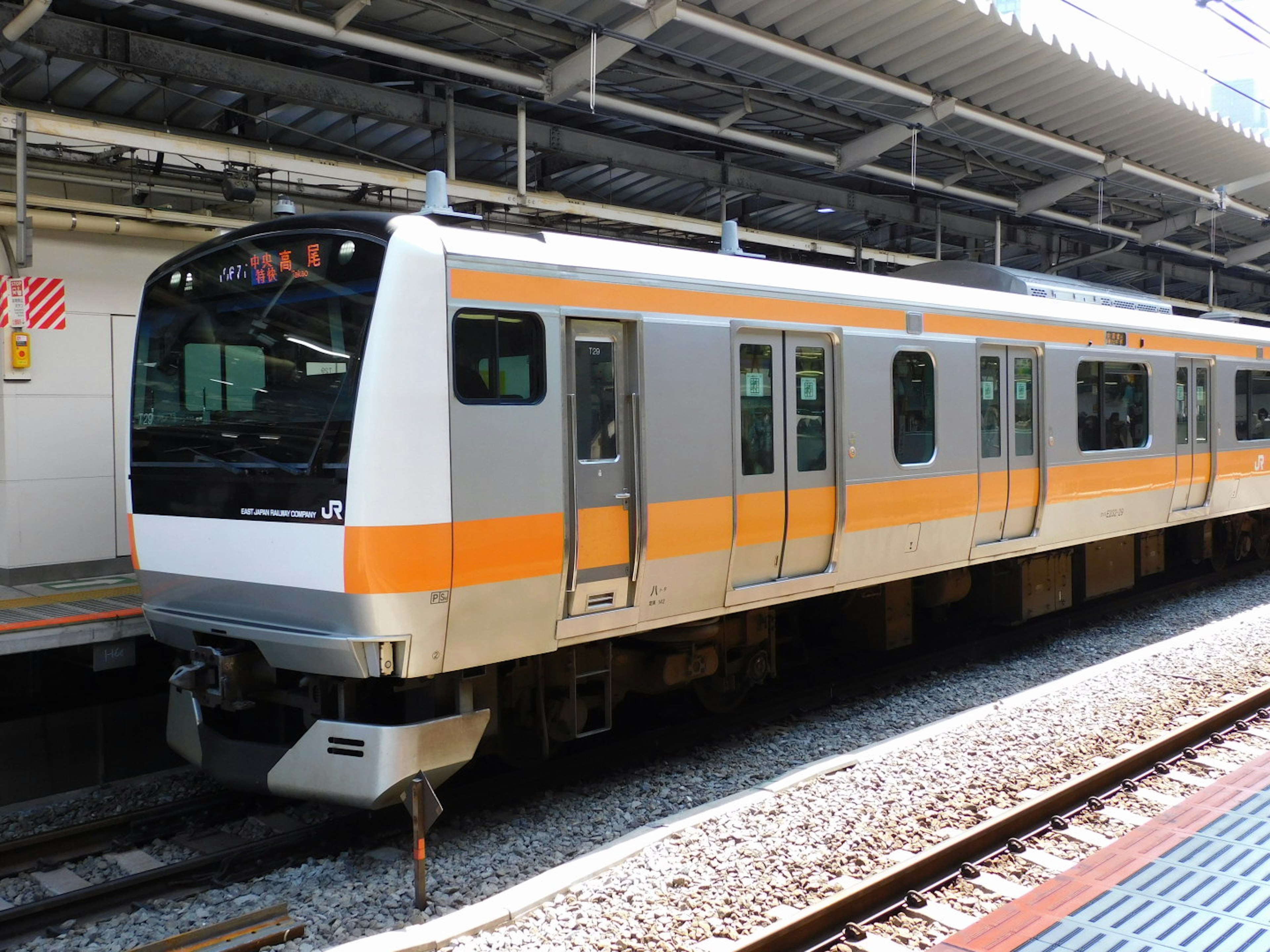 Tren con distintivas franjas naranjas estacionado en una estación