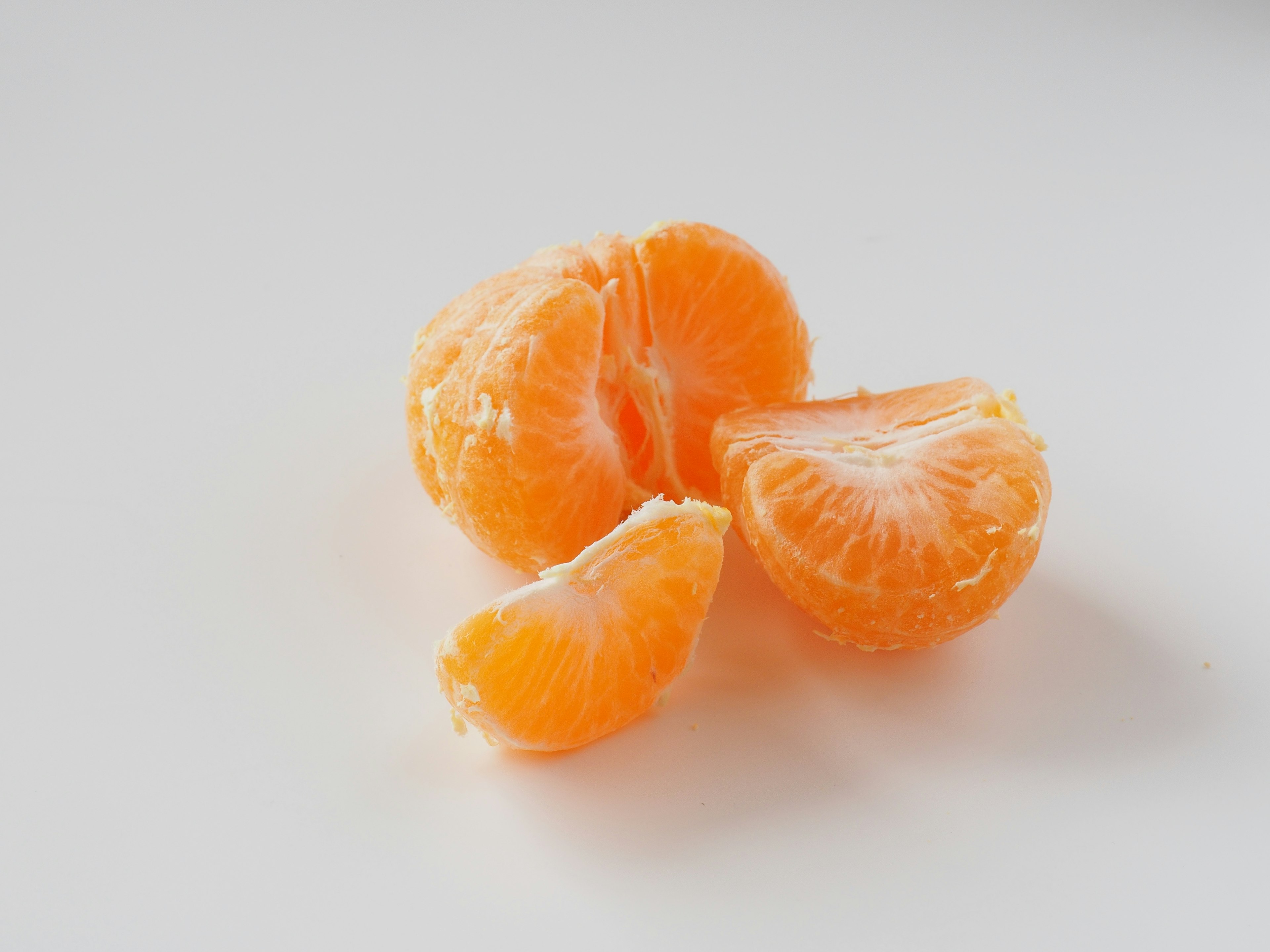 Vibrant orange segments of a mandarin placed on a white background