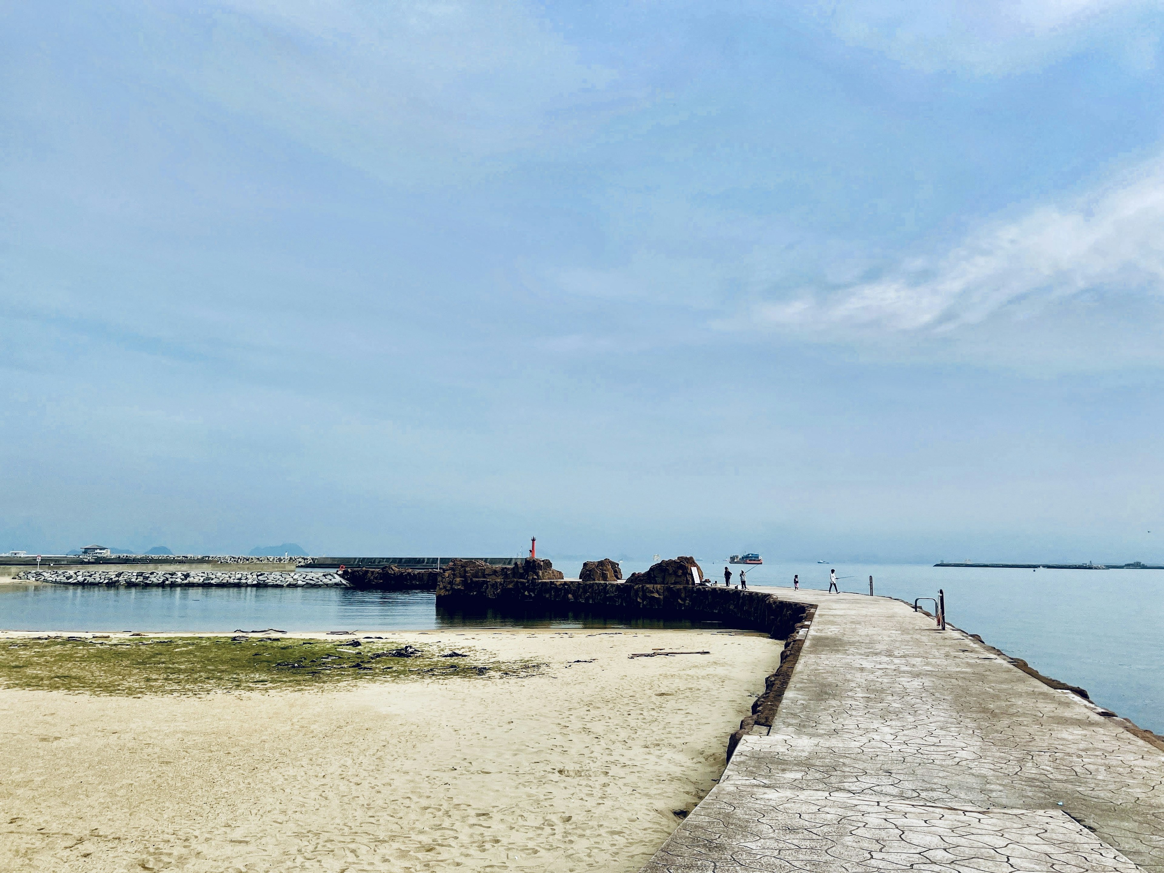 Tranquil beach scene with calm sea and blue sky Concrete pier extending into the water