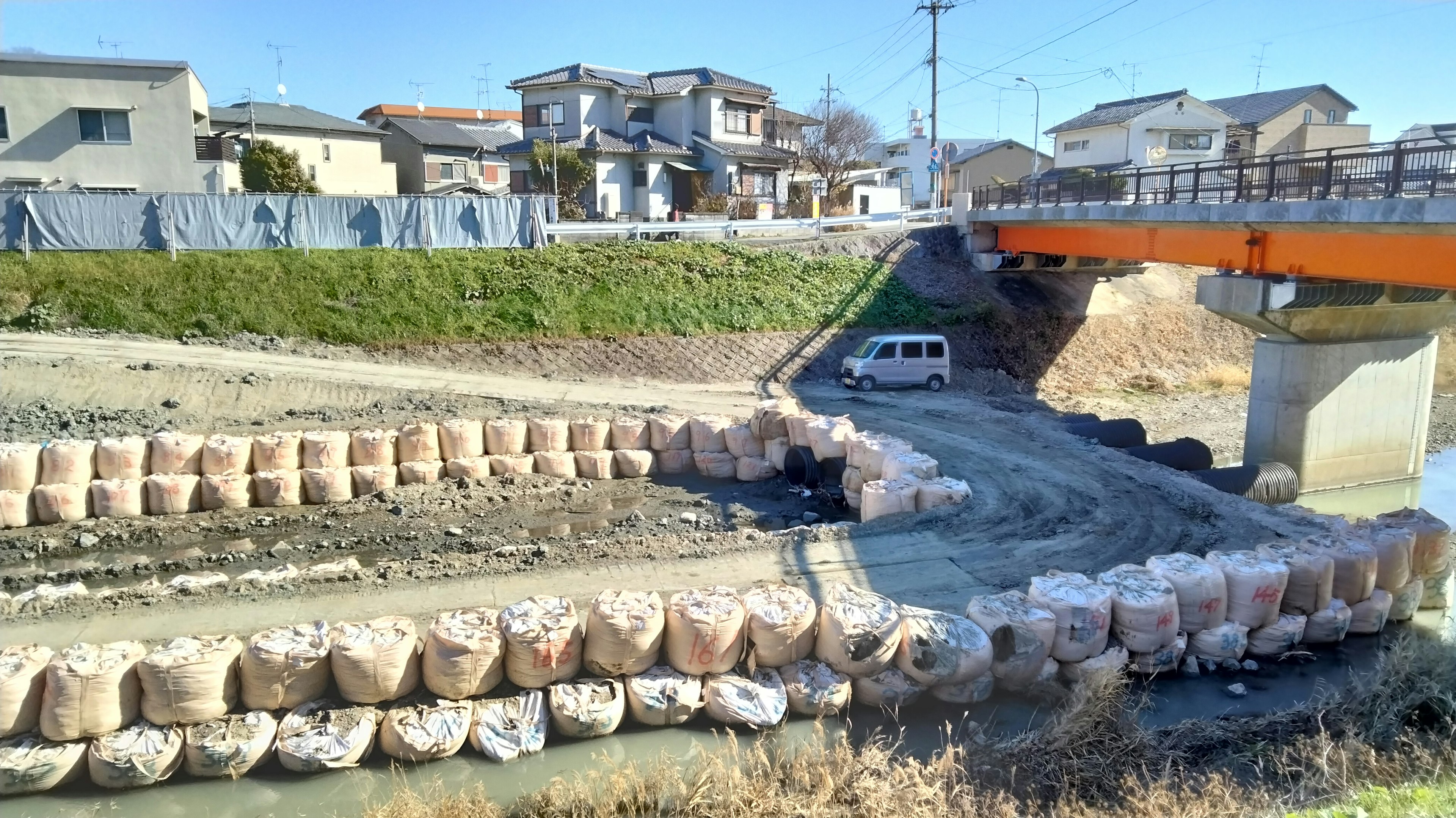 川の近くにある土嚢で囲まれた区域と橋の風景